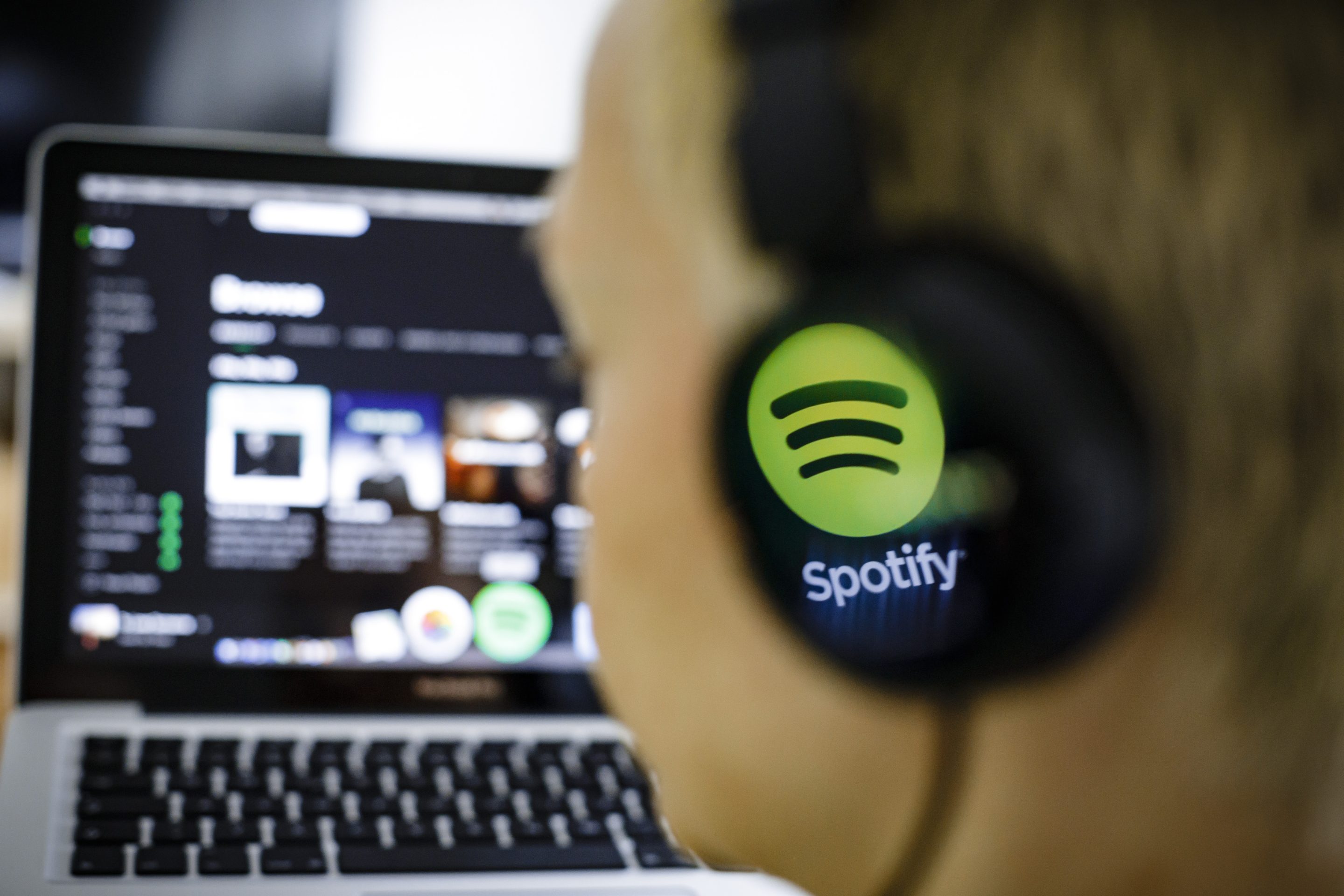 The logo of the music streaming service Spotify is reflected in a headphone.