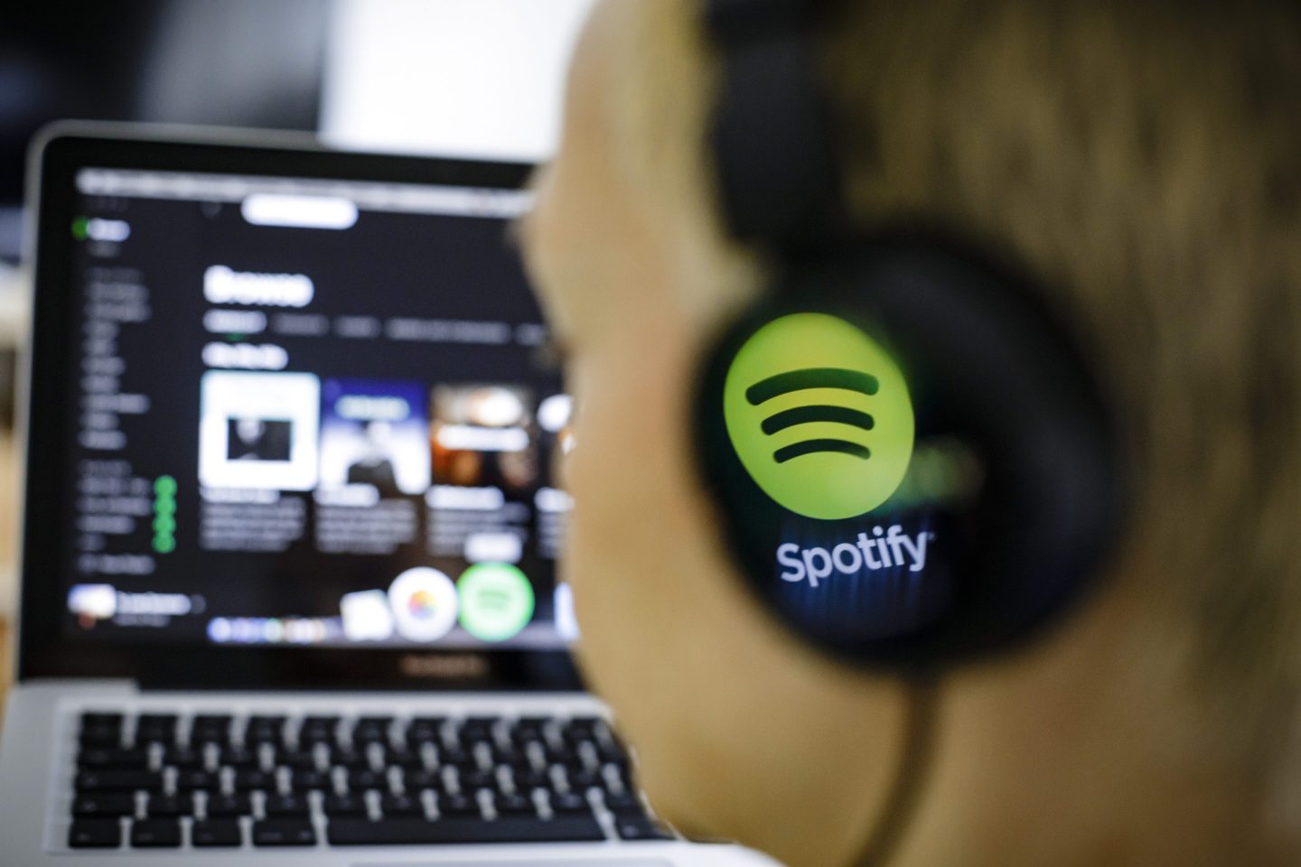The logo of the music streaming service Spotify is reflected in a headphone.