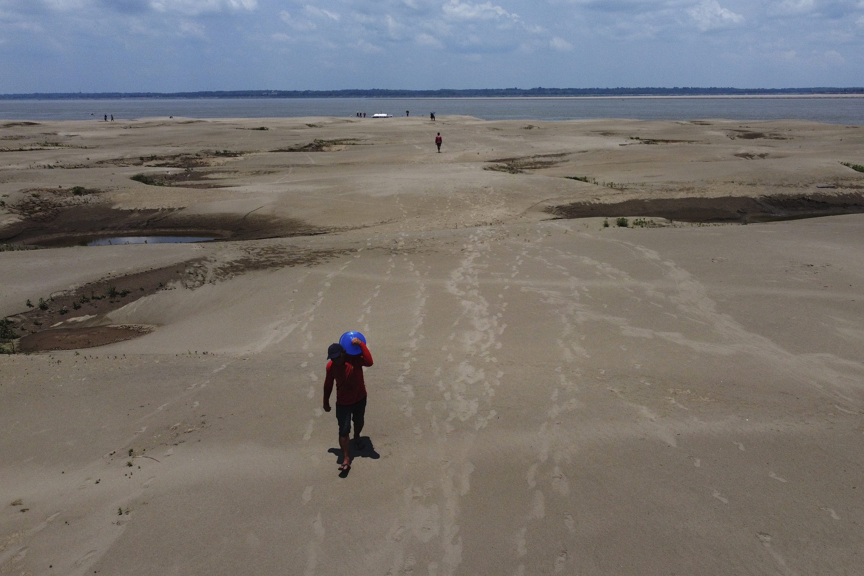Residents of a riverside community carry food and containers of drinking water from an aid distribution due to the ongoing drought in Careiro da Varzea, Amazonas state, Brazil, Oct. 24, 2023.