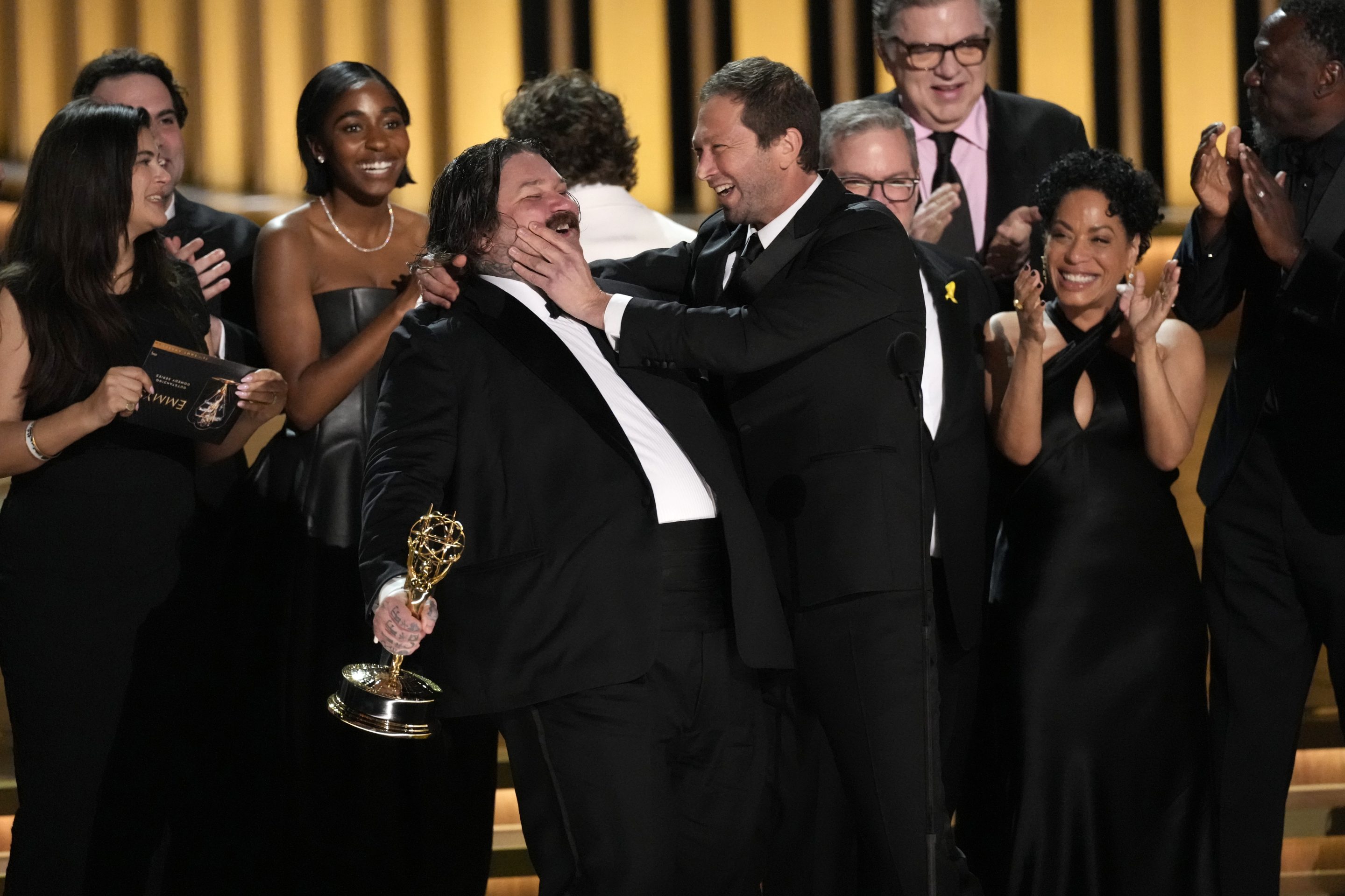 Matty Matheson, center, and Ebon Moss-Bachrach kiss as "The Bear" wins the award for outstanding comedy series during the 75th Primetime Emmy Awards on Jan. 15, 2024, at the Peacock Theater in Los Angeles.