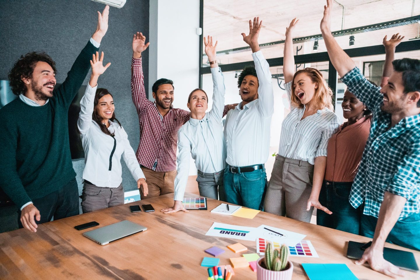 people standing around a table with their hands raised