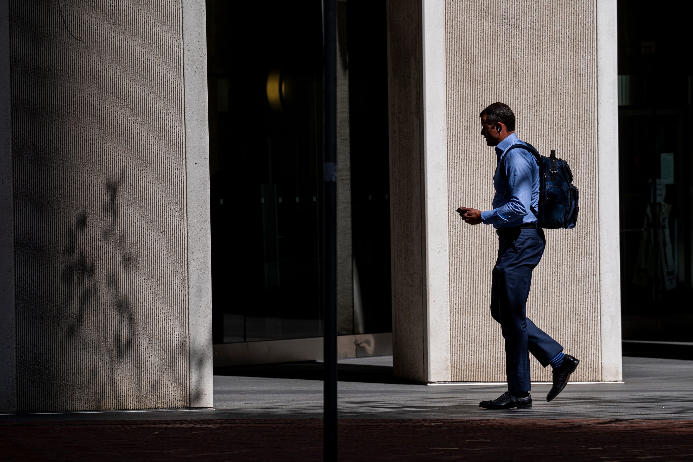 A man dressed in business casual attire walks into an office building on Market Street in the financial district of San Francisco, California, U.S., on May 9, 2022.
