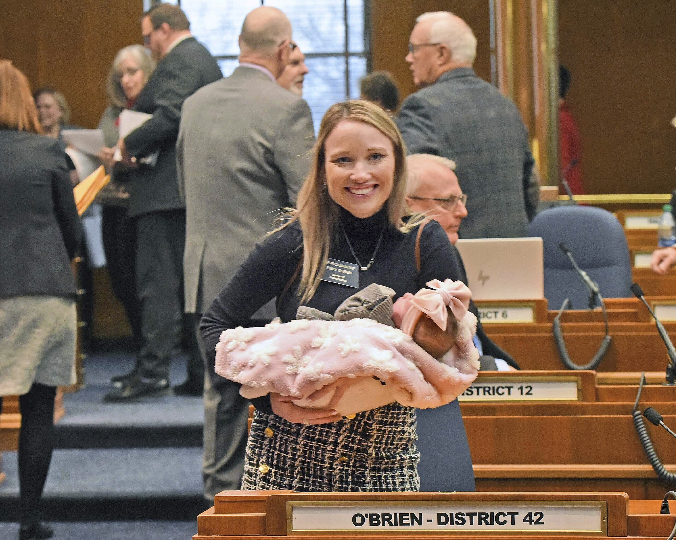 Rep. Emily O'Brien R-Grand Forks carries daughter Jolene Green, 3 weeks, into the House chamber, Dec. 6, 2022, in Bismarck, N.D.