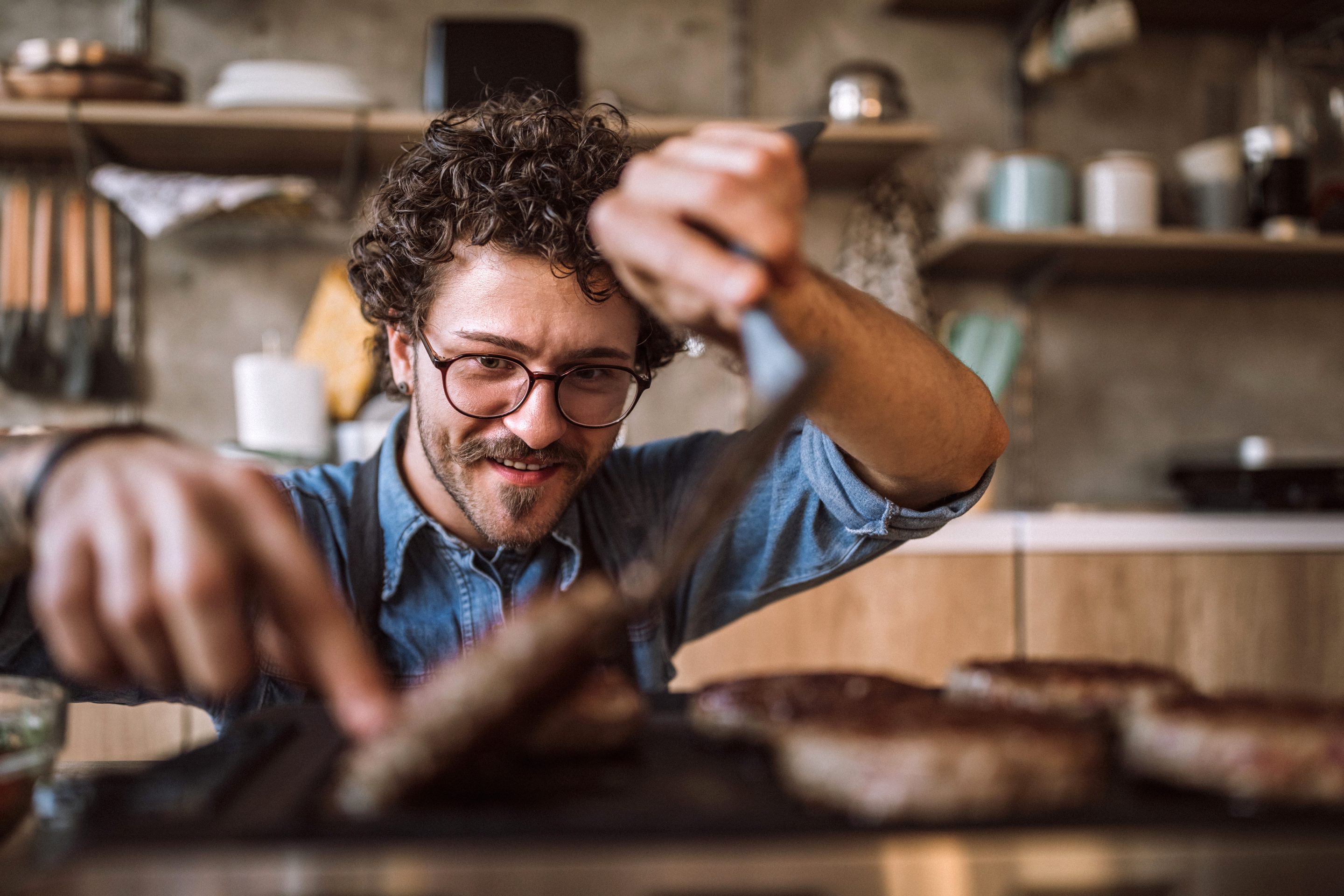Hipster man turns a burger on a grill