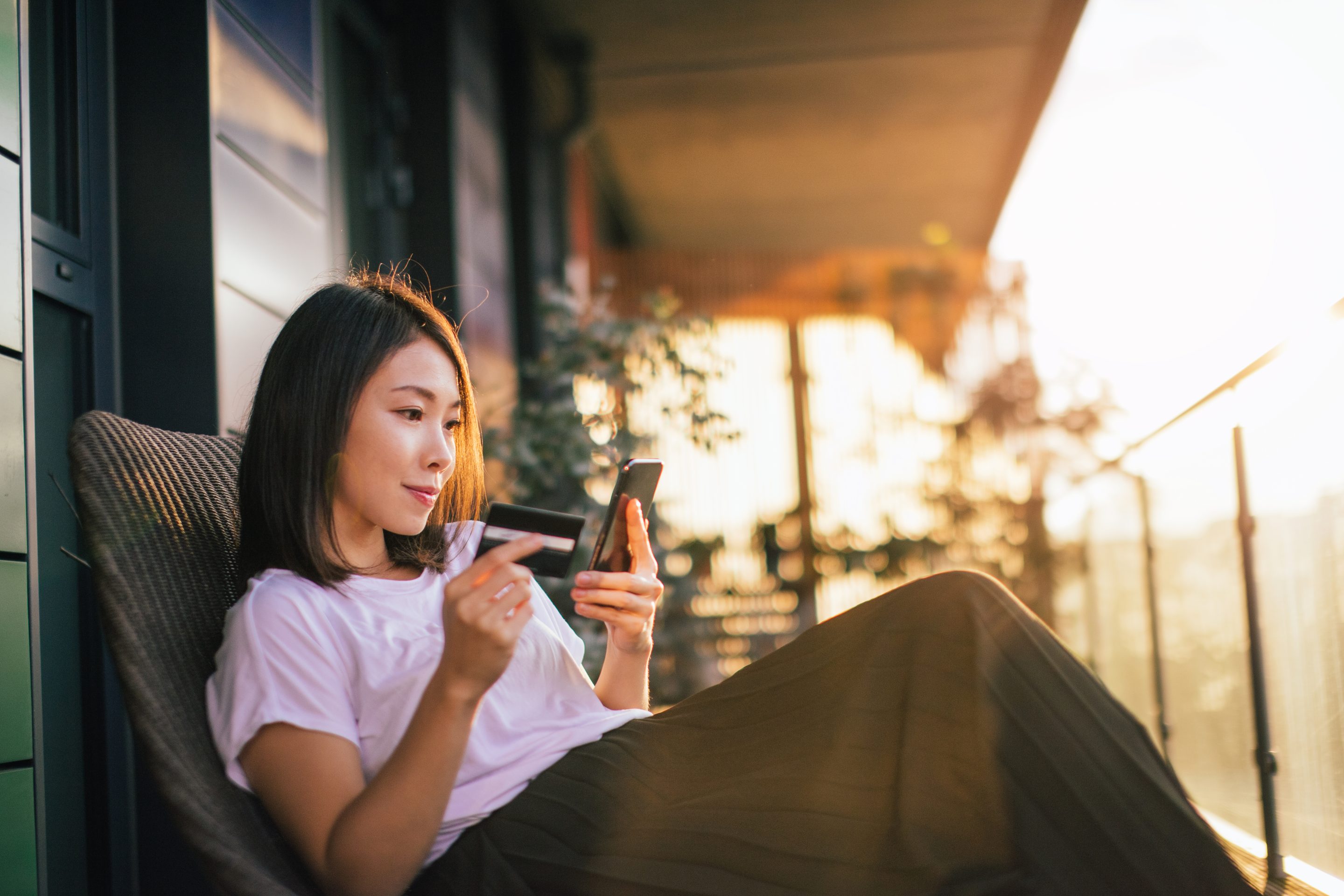 Young woman using smart phone and credit card to make online payments.