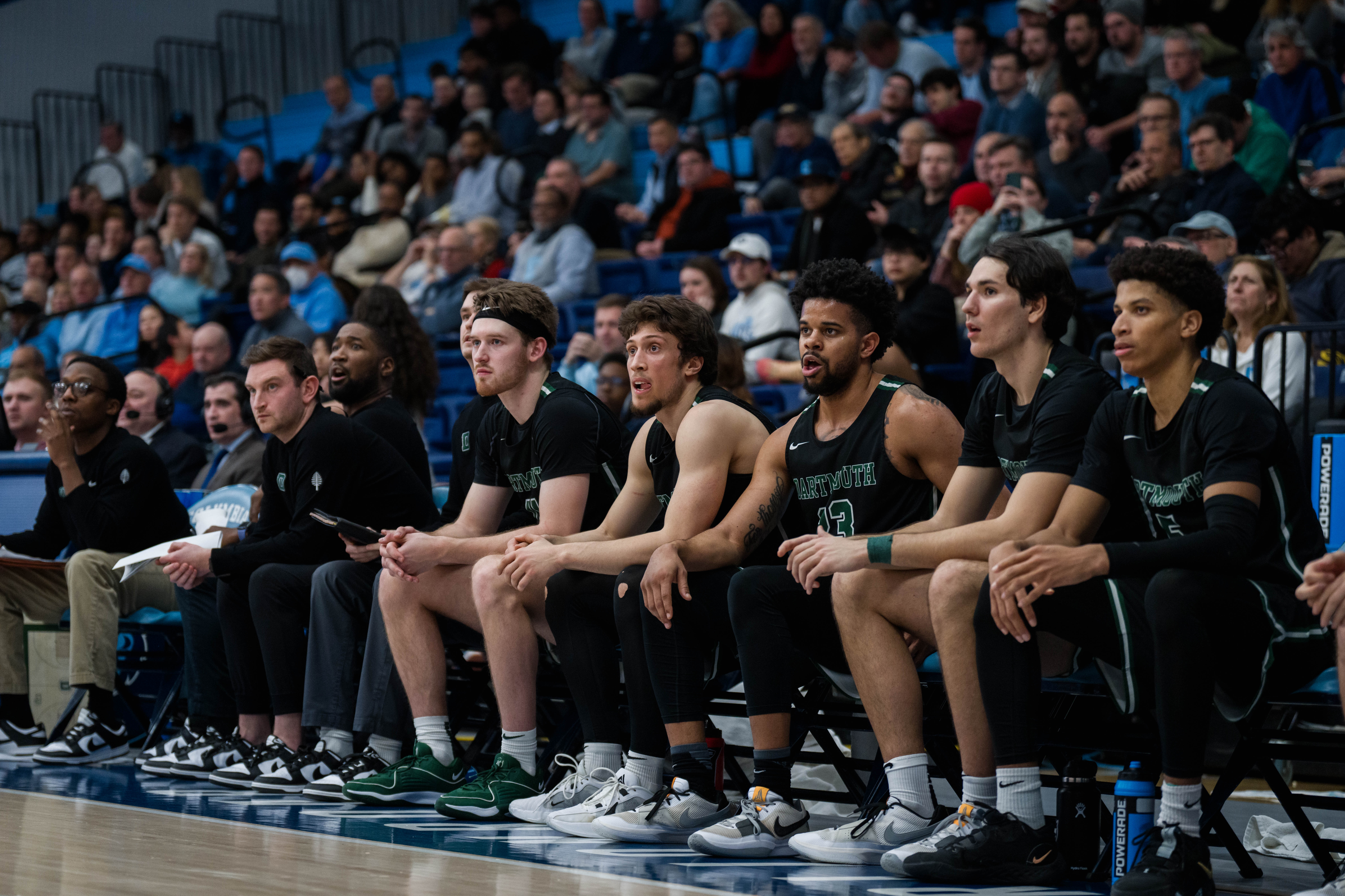 The Dartmouth men's basketball team sitting on a bench.