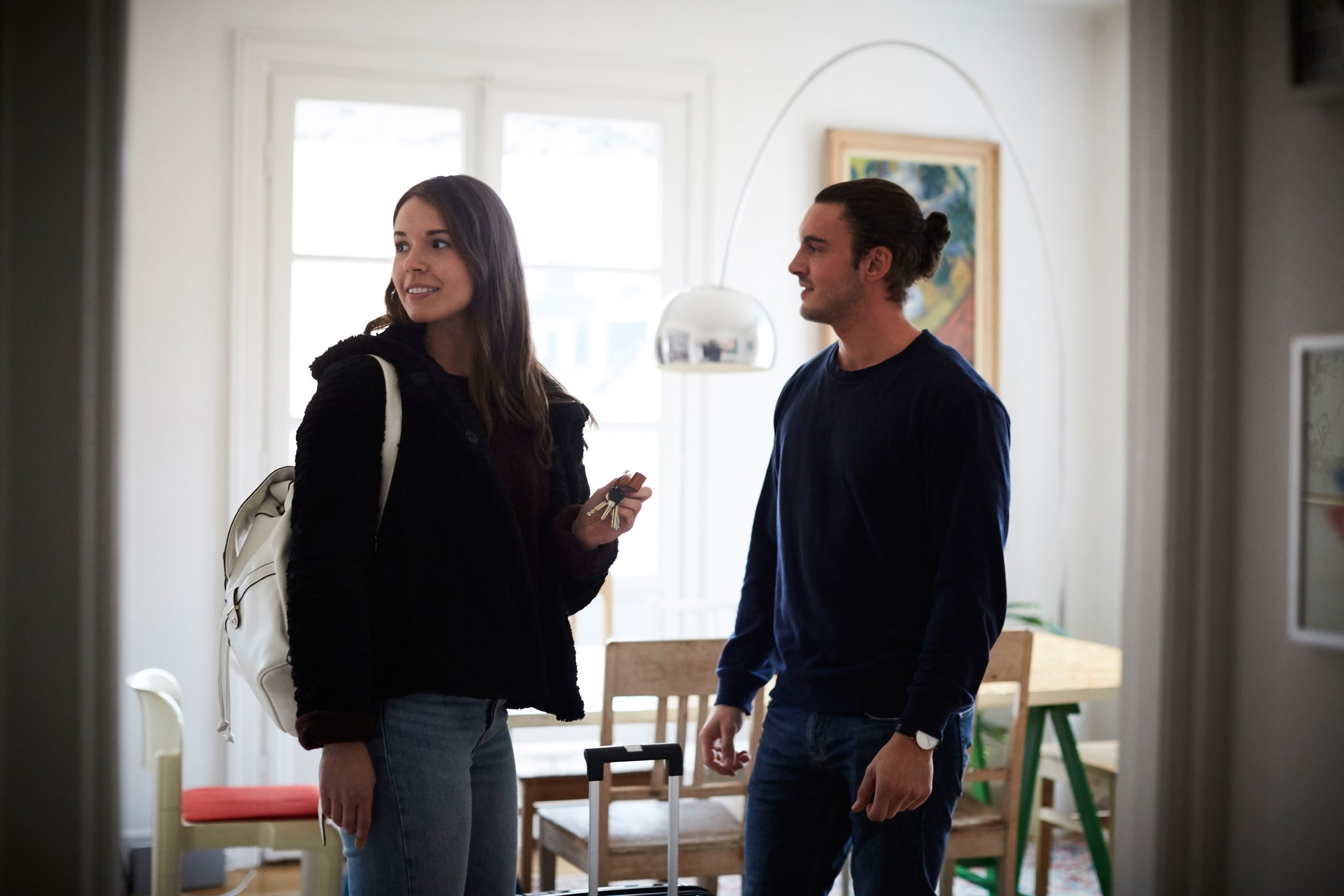 Smiling man and woman standing in apartment on sunny day