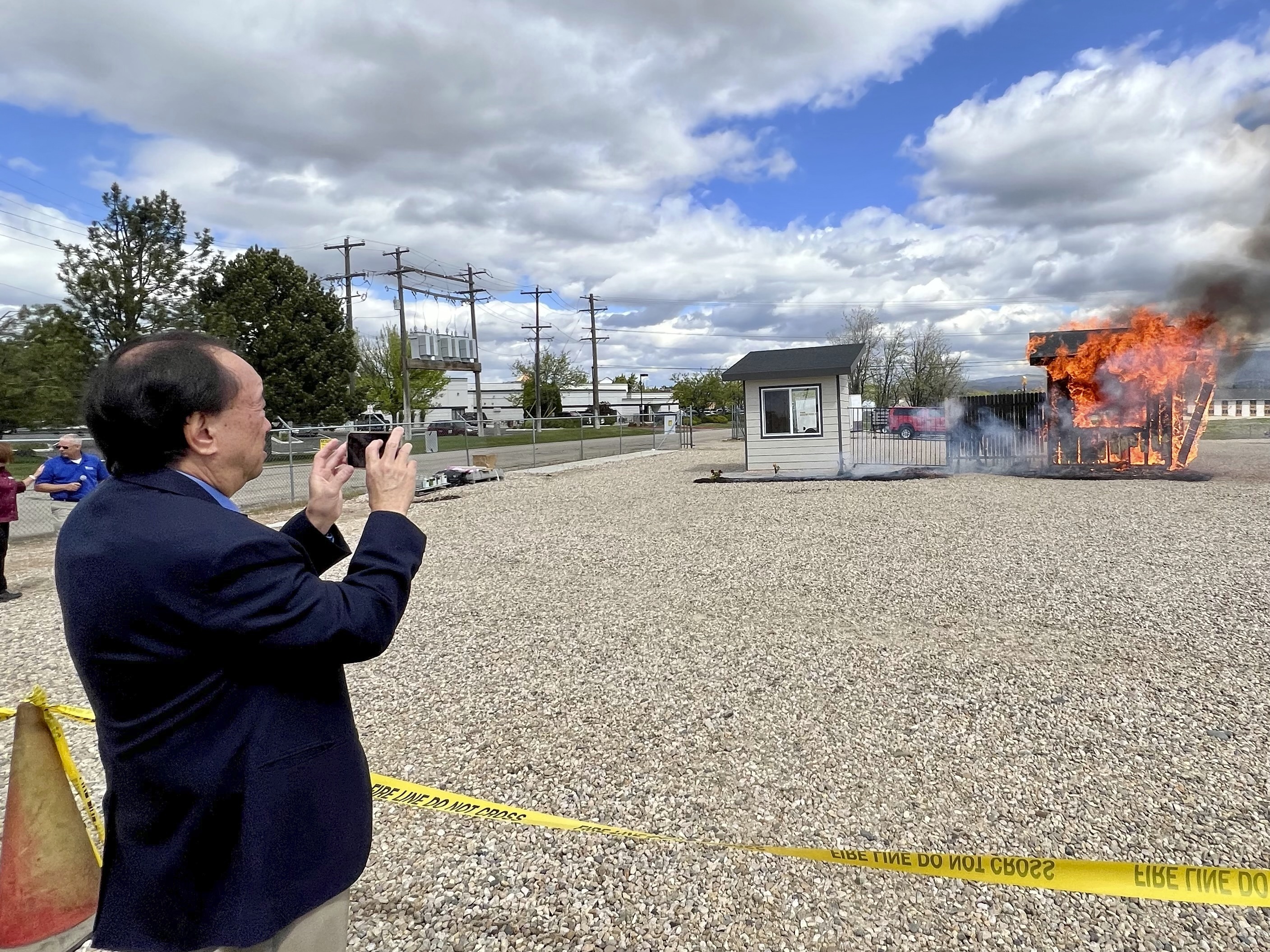 Hawaii Insurance Commissioner Gordon Ito films a wildfire burn risk demonstration at the National Interagency Fire Center in Boise, Idaho, on April 29, 2024.