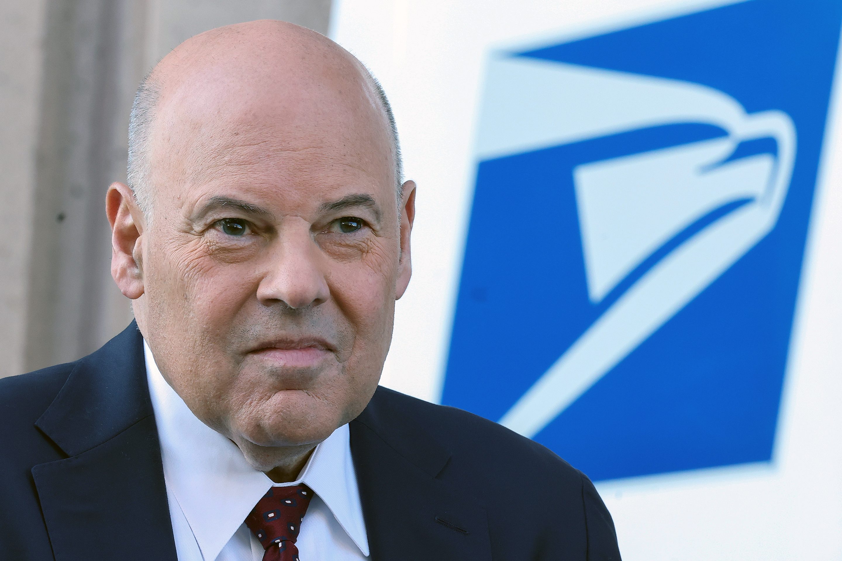 Louis DeJoy in front of a USPS van