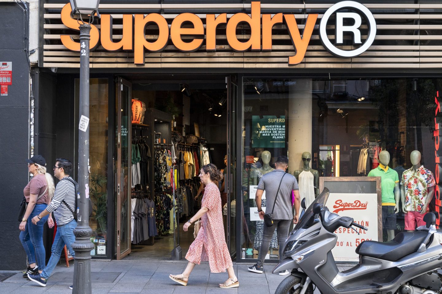 people walking on a busy street outside a superdry store