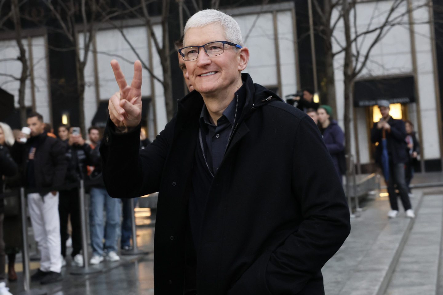 Tim Cook smiles and flashes a "peace" sign.