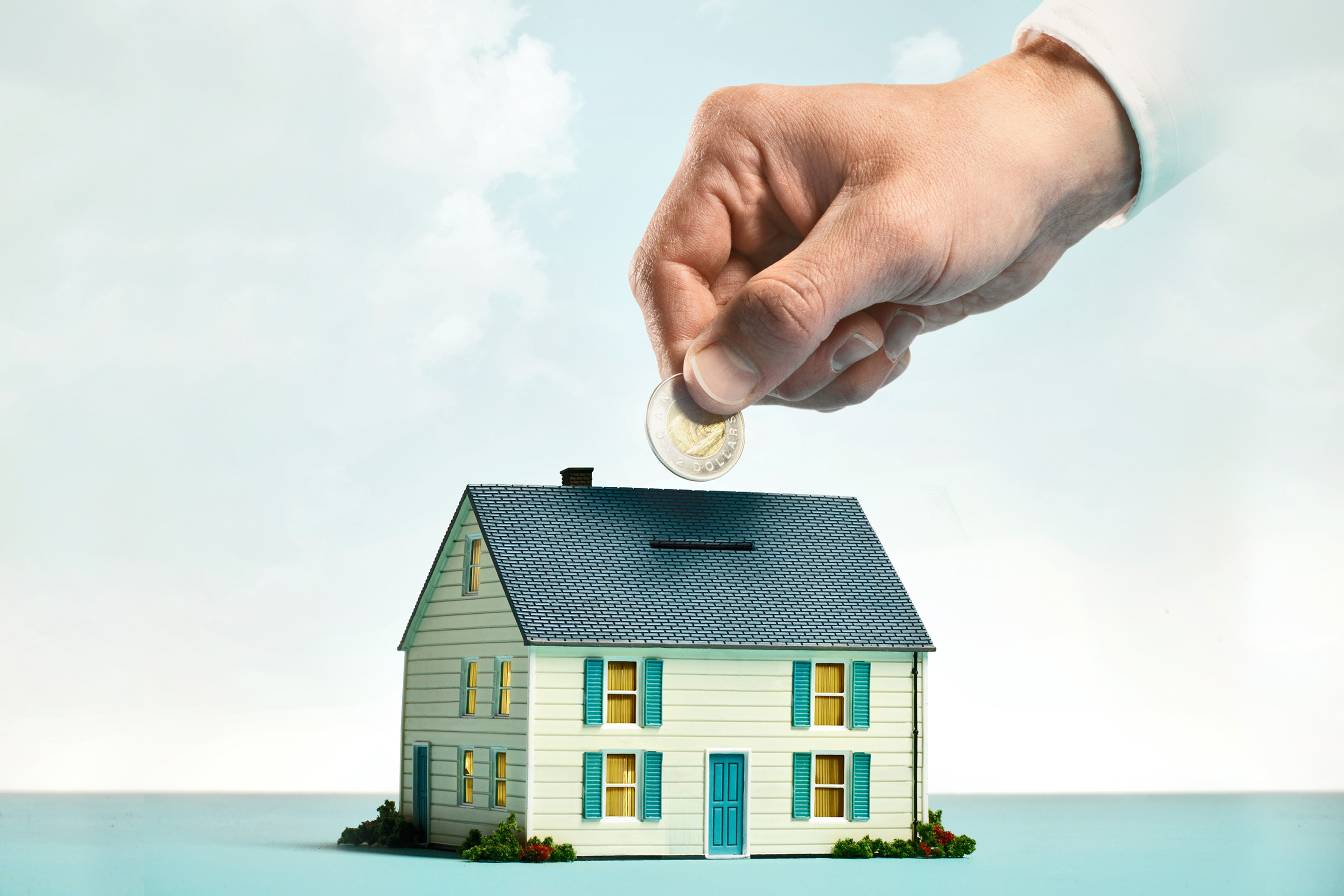 Hand putting coins into house piggy bank