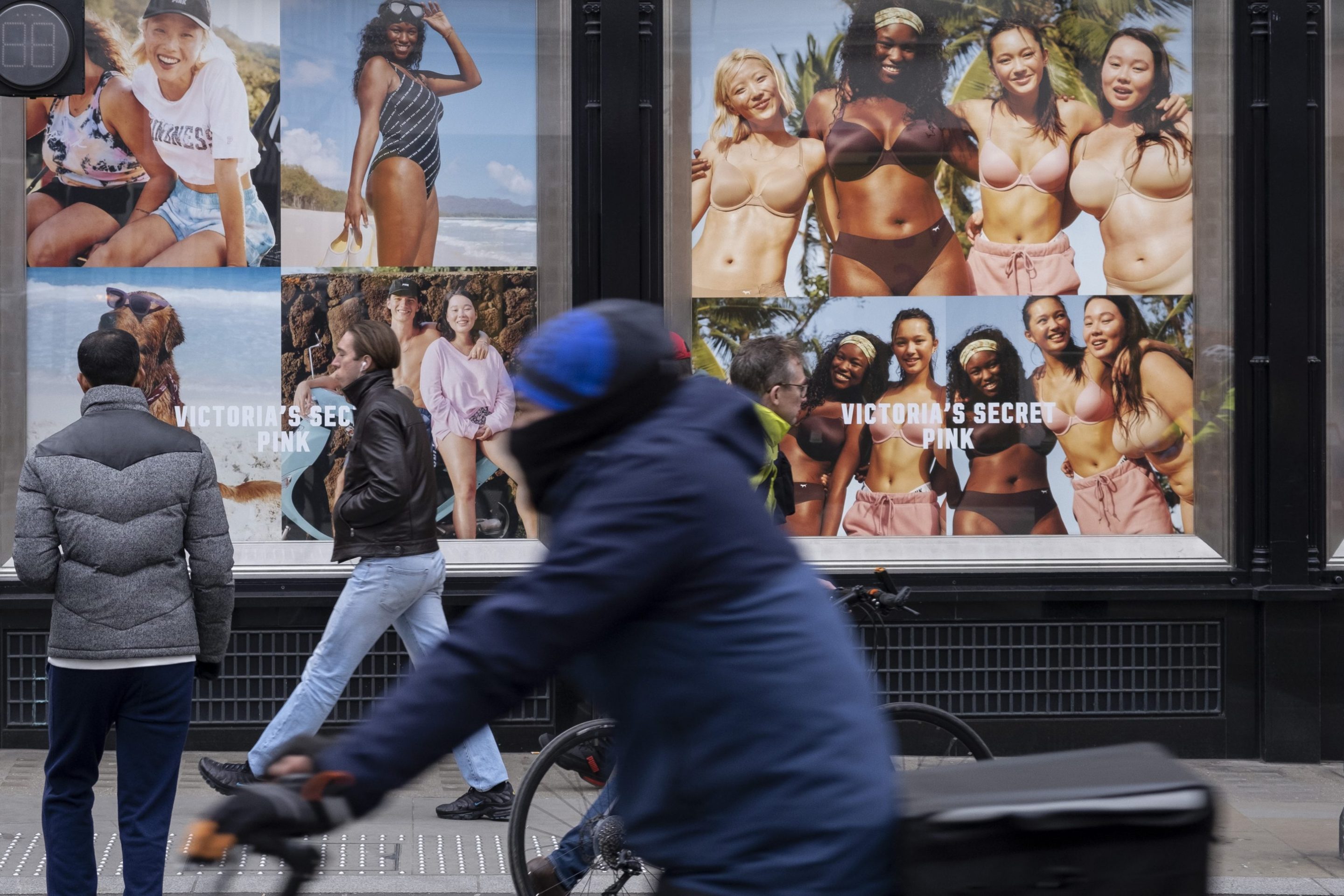 Passers by interact with advertising photographs featuring models of all sizes and mixed ethnicities in the shop windows of exclusive lingerie store Victoria's Secret
