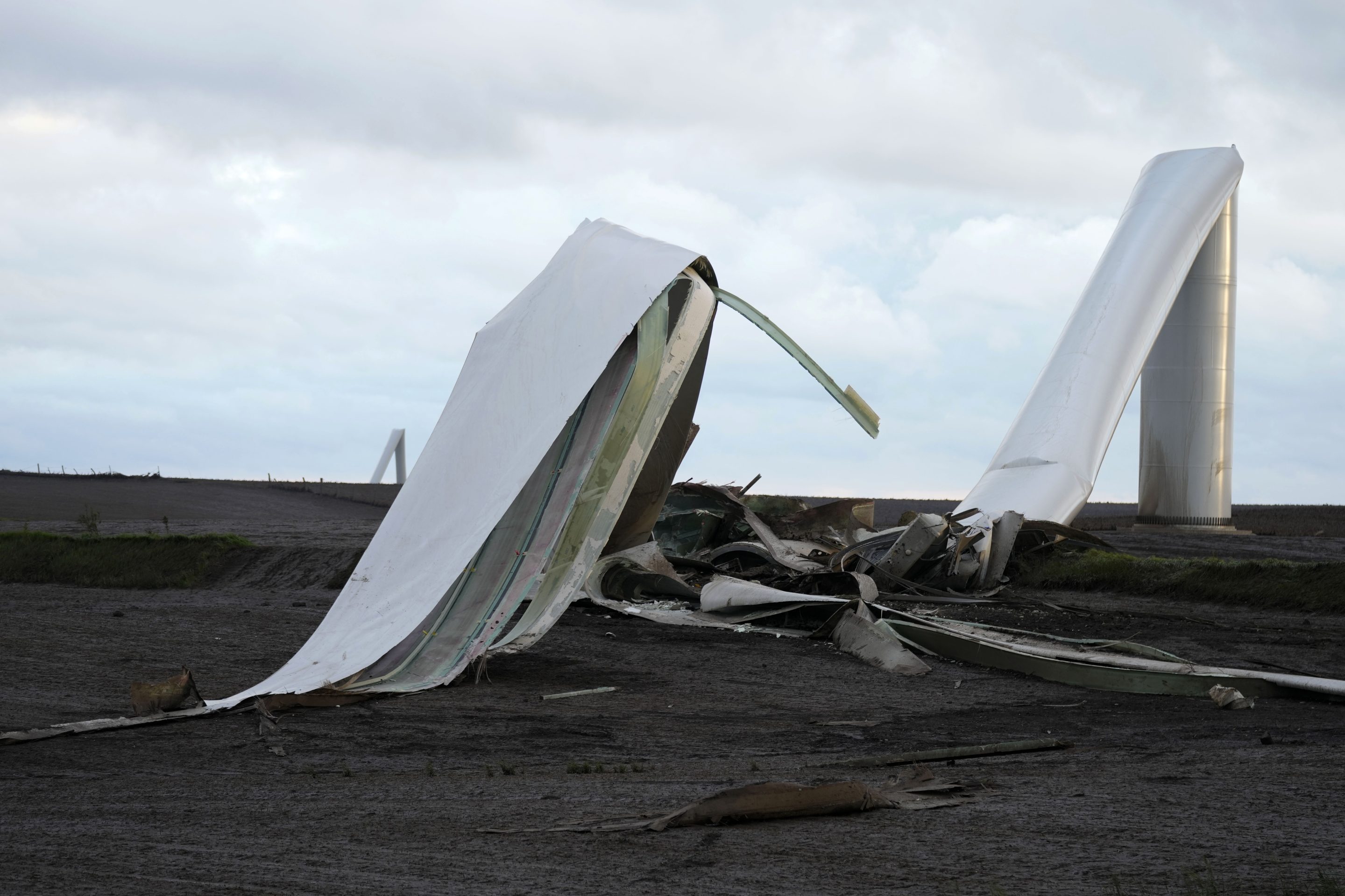 The remains of a tornado-damaged wind turbine touch the ground in a field, on May 21, 2024, near Prescott, Iowa.