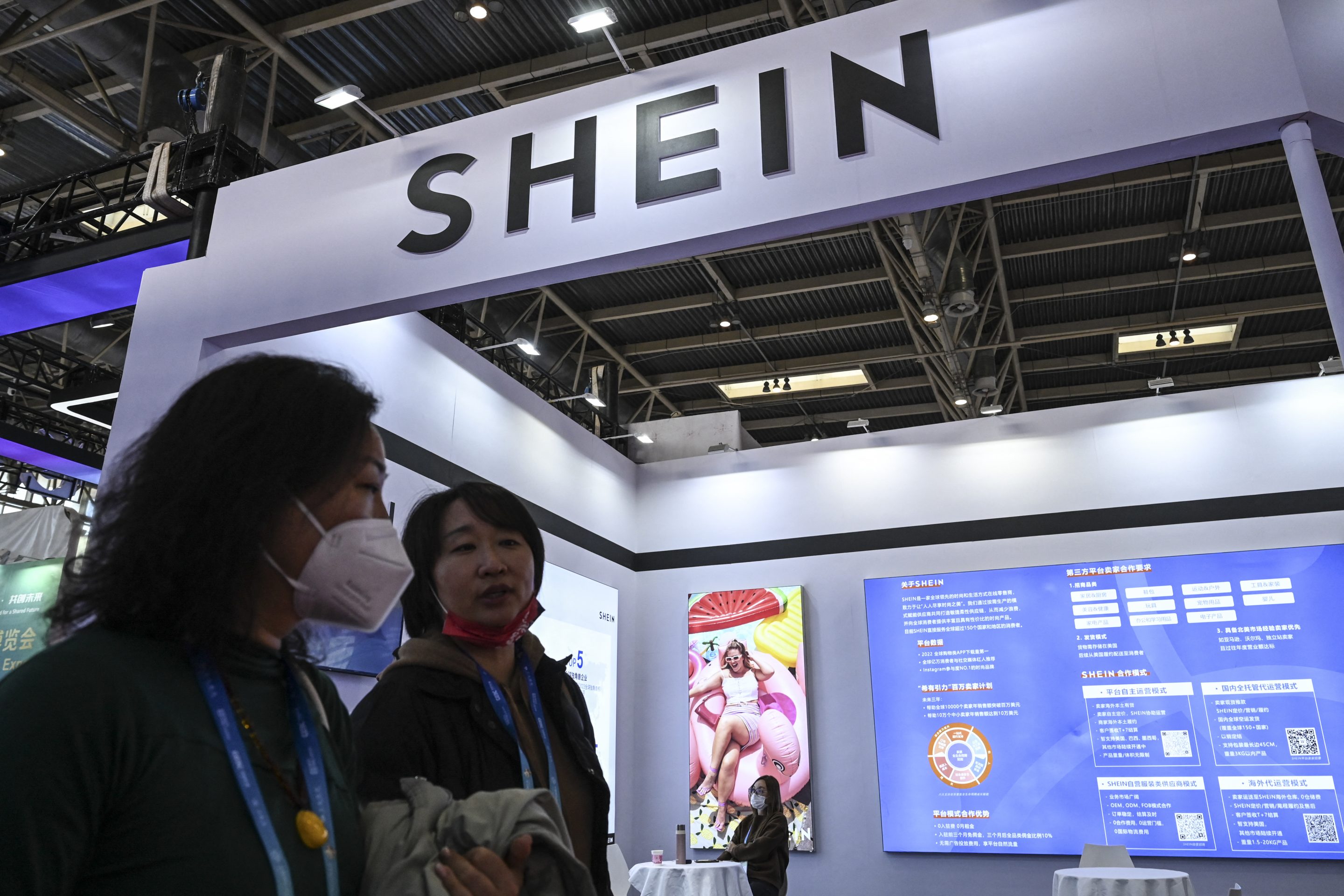 People walk past the booth of fast fashion e-commerce company SHEIN during the China International Supply Chain Expo.