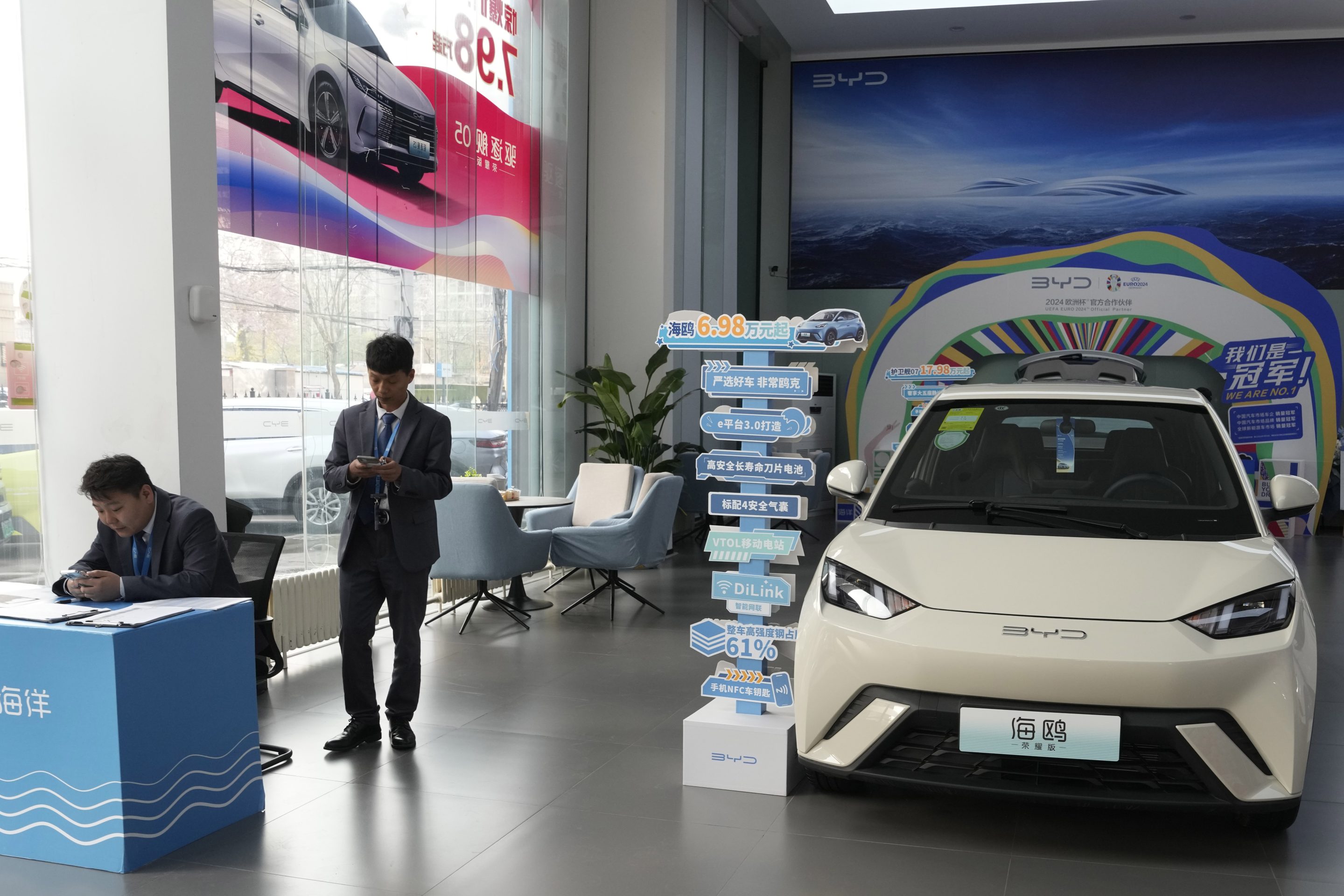 Sales staff stand near the Seagull electric vehicle from Chinese automaker BYD at a showroom in Beijing on April 10, 2024.