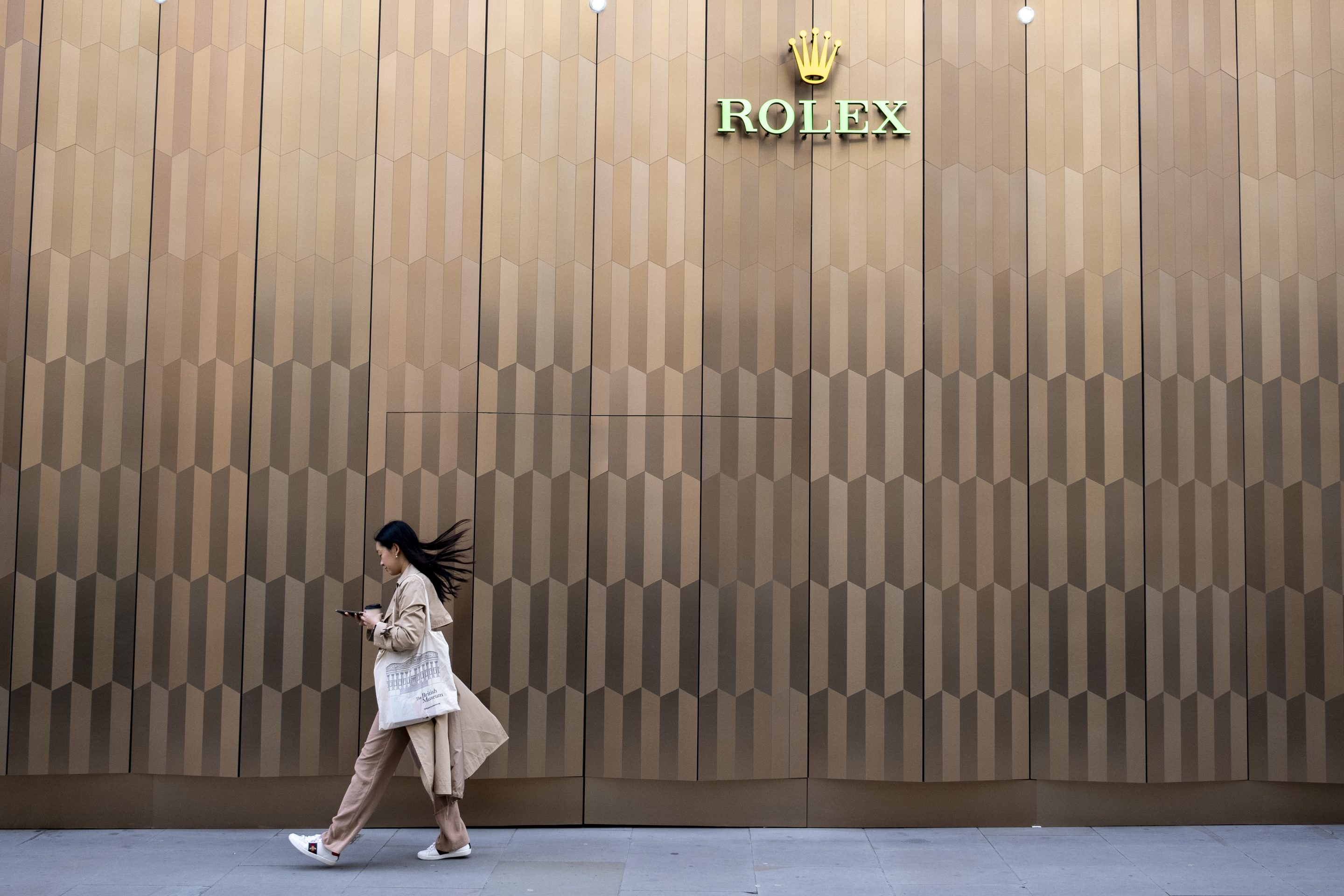 Woman walks past a Rolex store