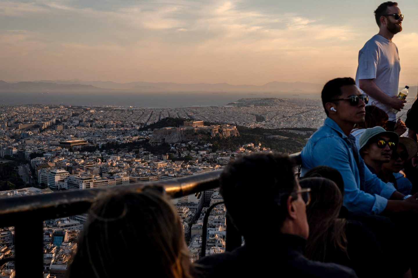Visitors watch the sunset over the city from Lycabettus Hill in Athens, Greece