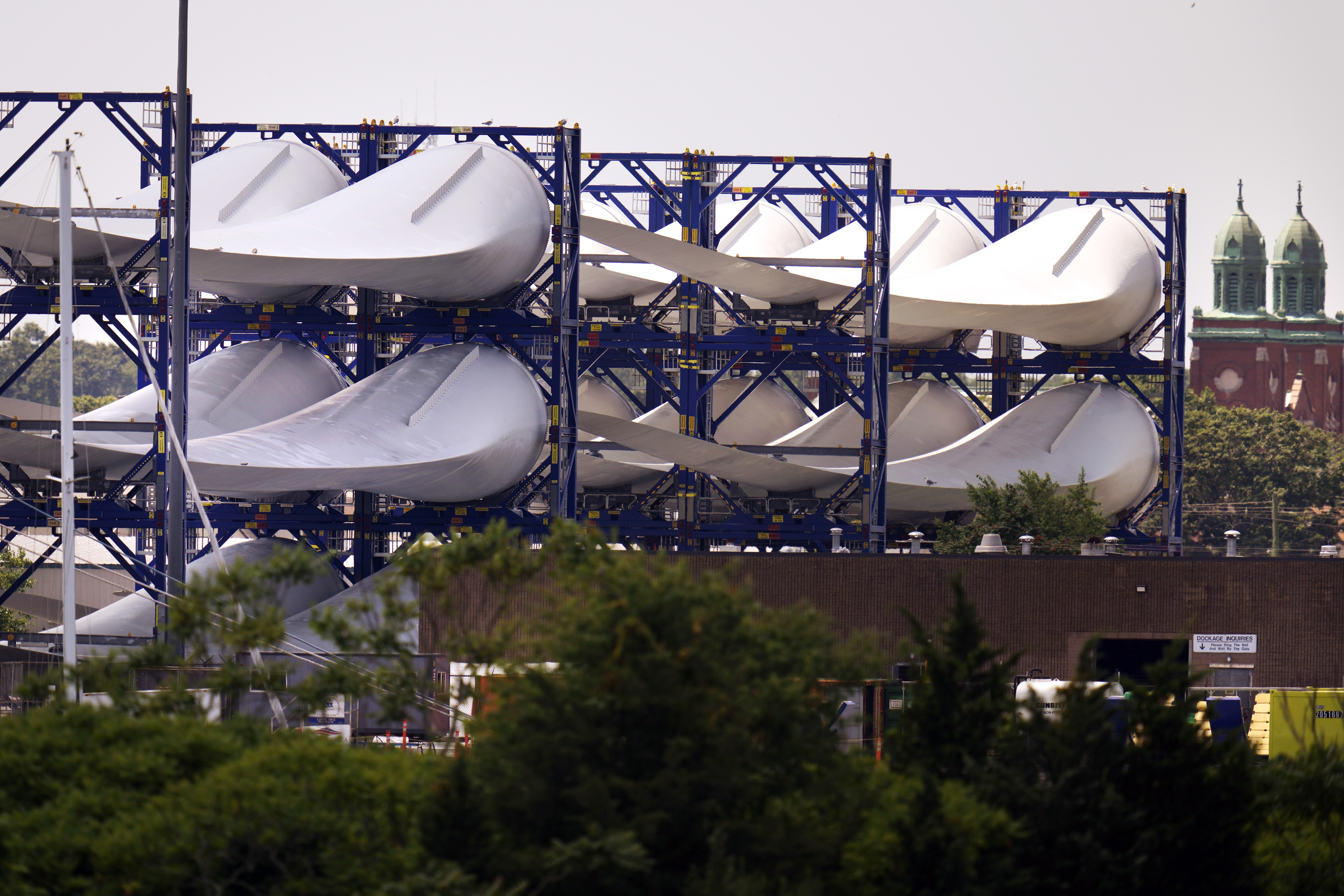 Giant wind turbine blades for the Vineyard Winds project are stacked on racks in the harbor, July 11, 2023, in New Bedford, Mass. 