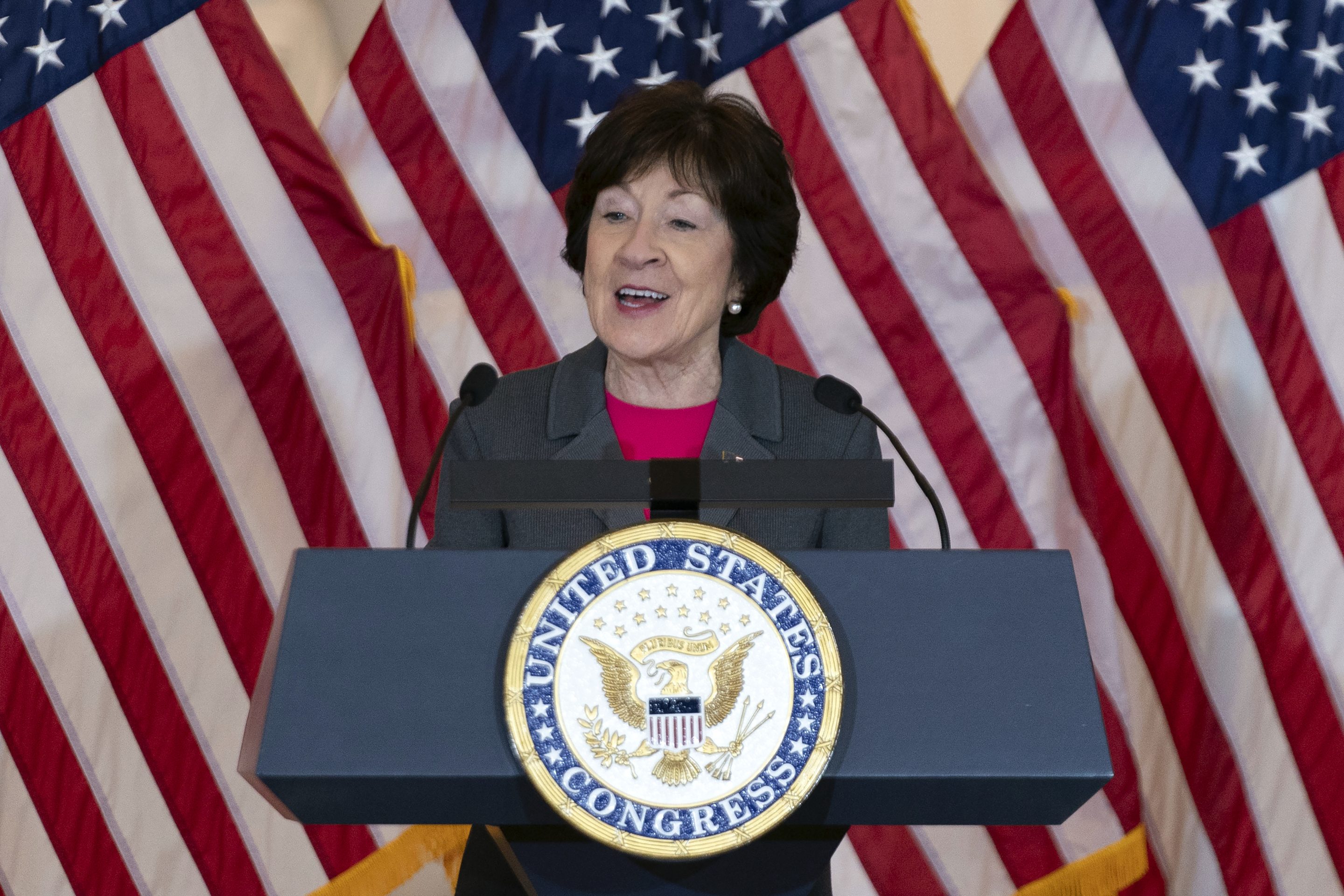 Sen. Susan Collins stands in front of US flags