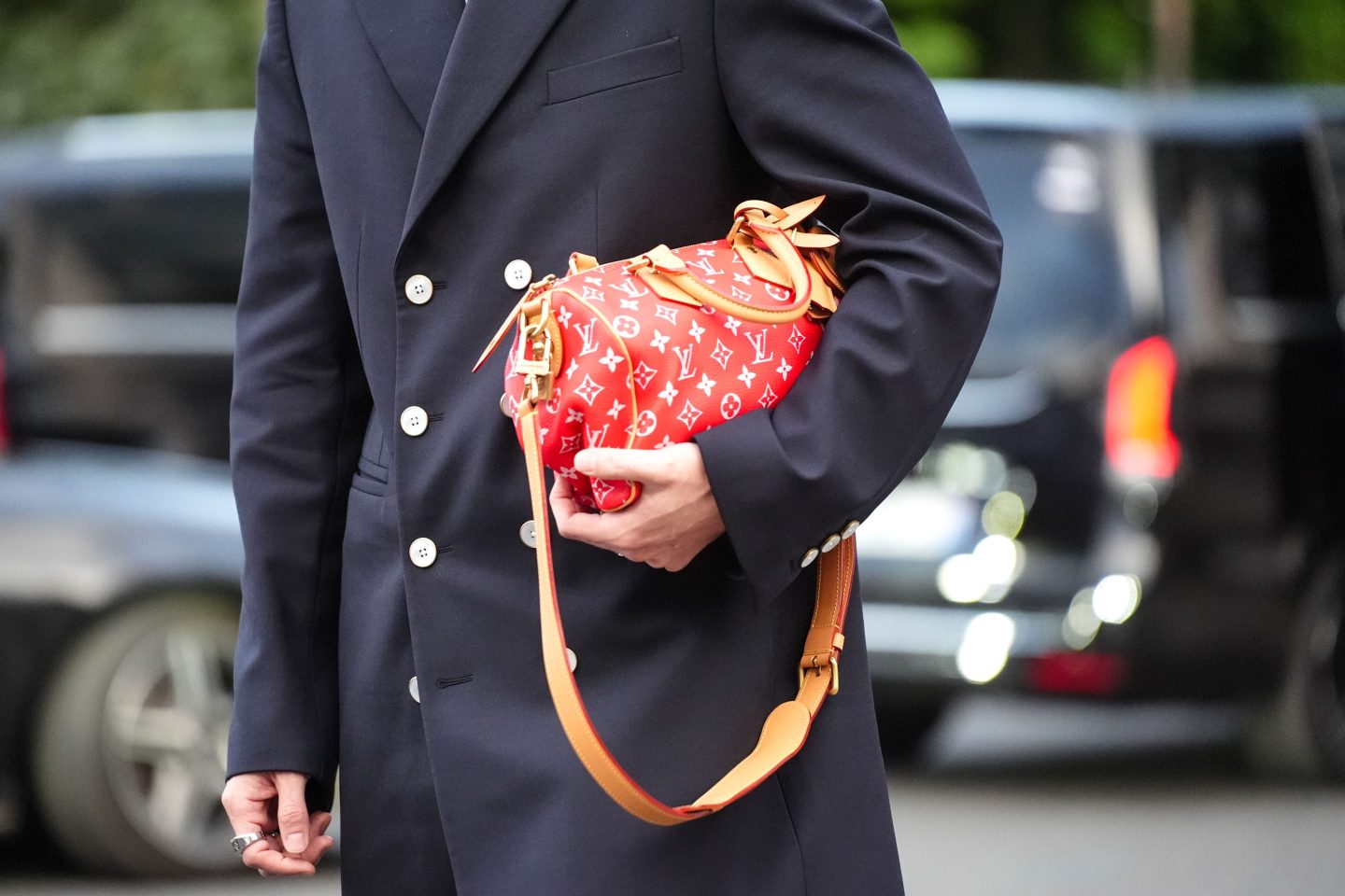 A guest wears Louis Vuitton red leather bag, outside Louis Vuitton, during the Paris Fashion Week Menswear Spring/Summer 2025 on June 18, 2024 in Paris, France.