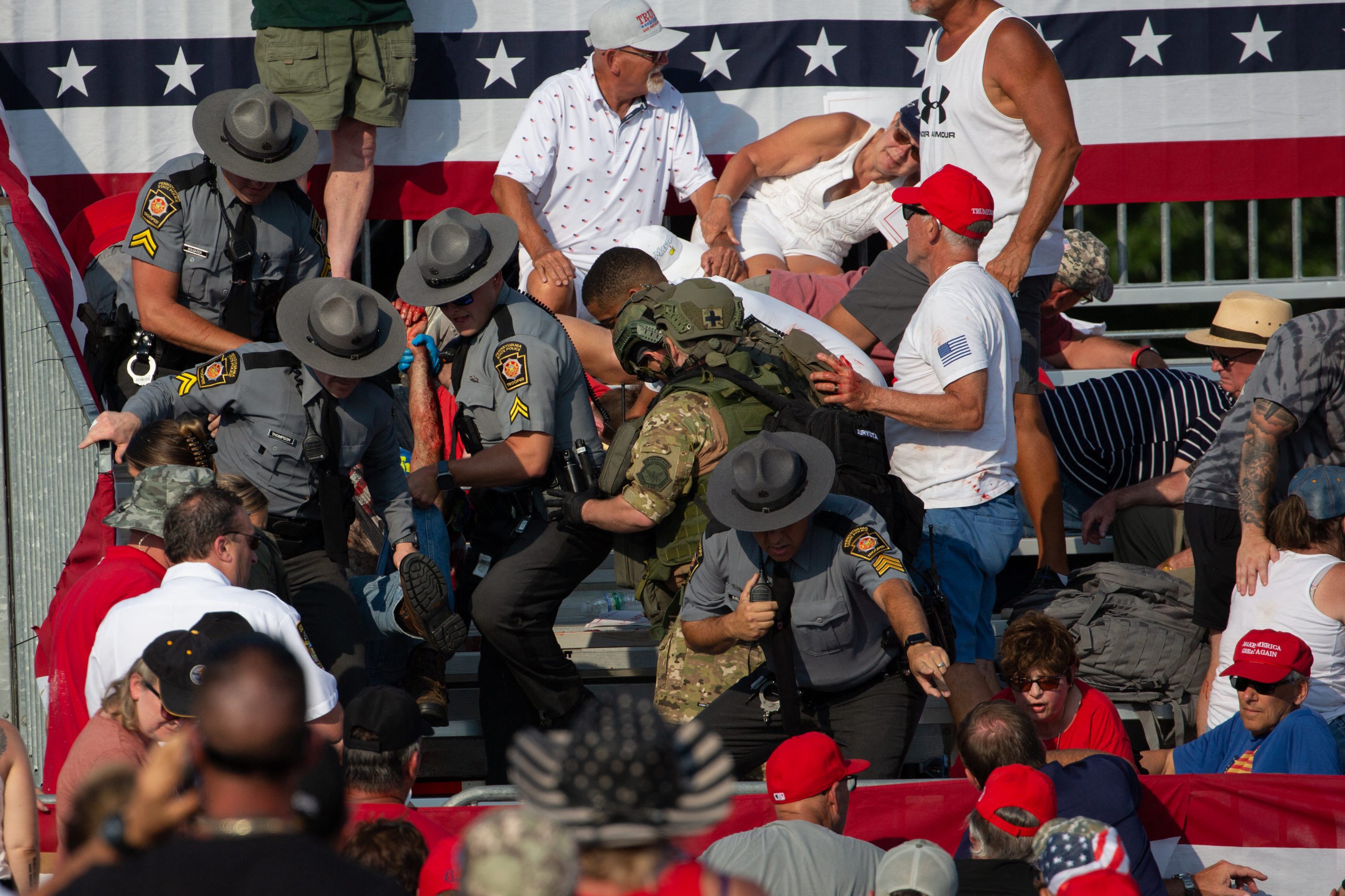 A person is removed by state police from the stands after guns were fired at Donald Trump on Saturday.