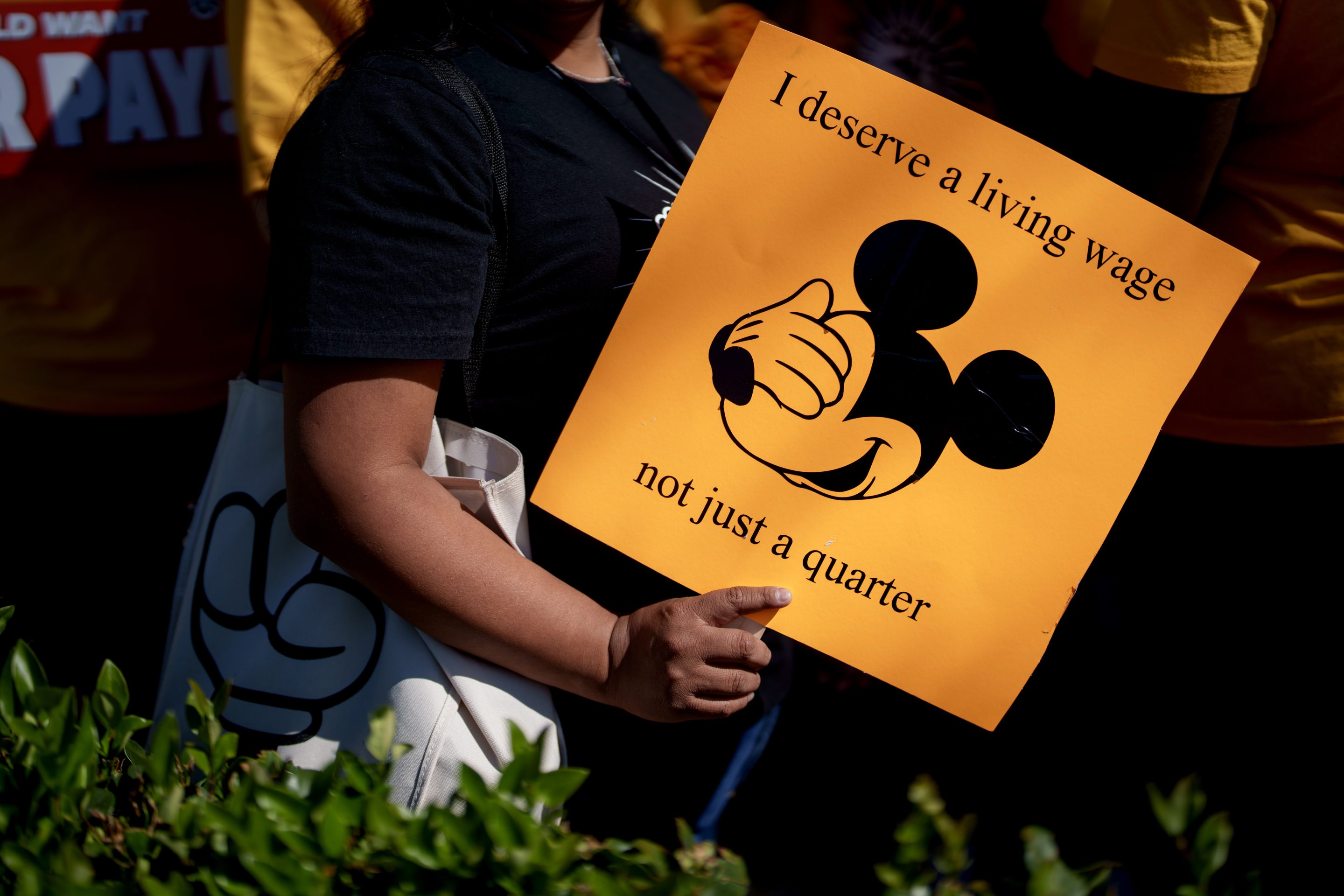 A Walt Disney Co. employee supporter holds a sign during a rally in Anaheim, California, US, on Wednesday, July 17, 2024. Last month 1,700 Disneyland Resort