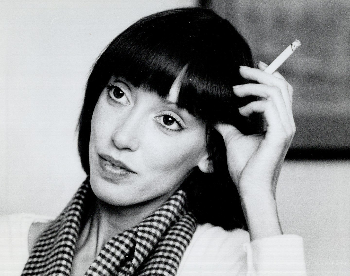 A black-and-white closeup of Shelley Duvall, holding a cigarette