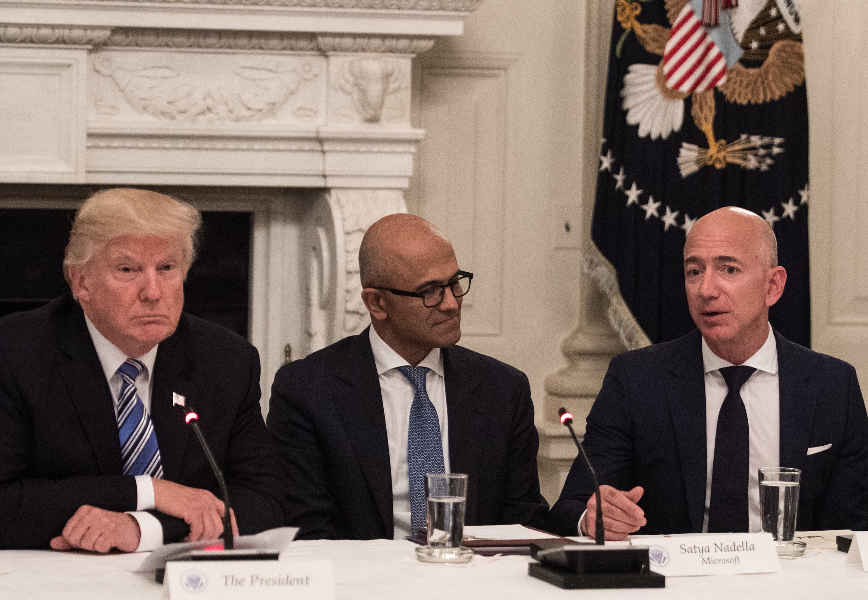 U.S. President Donald Trump (L) and Microsoft CEO Satya Nadella (C) listen to Amazon CEO Jeff Bezos (R) during an American Technology Council roundtable at the White House.