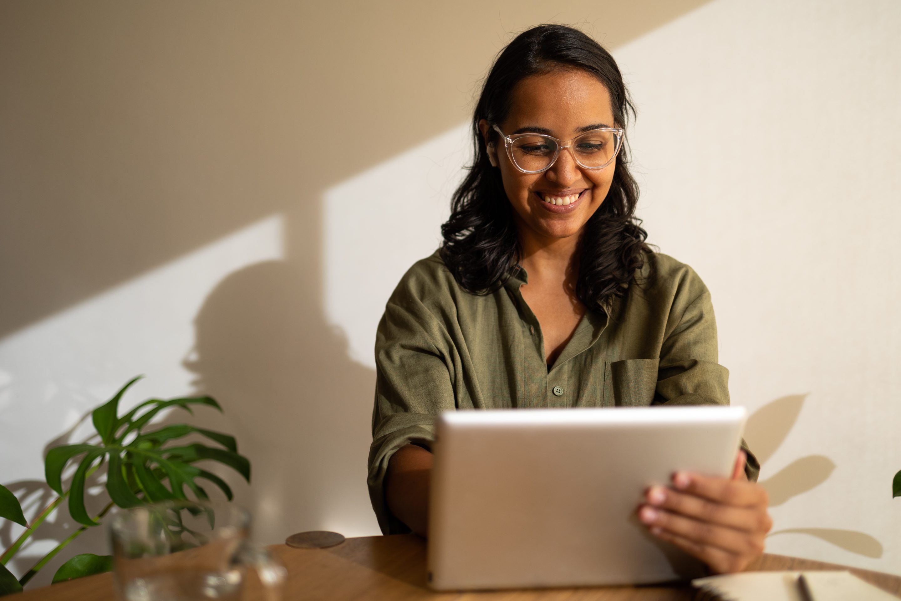 Woman smiling while working from home on her digital tablet