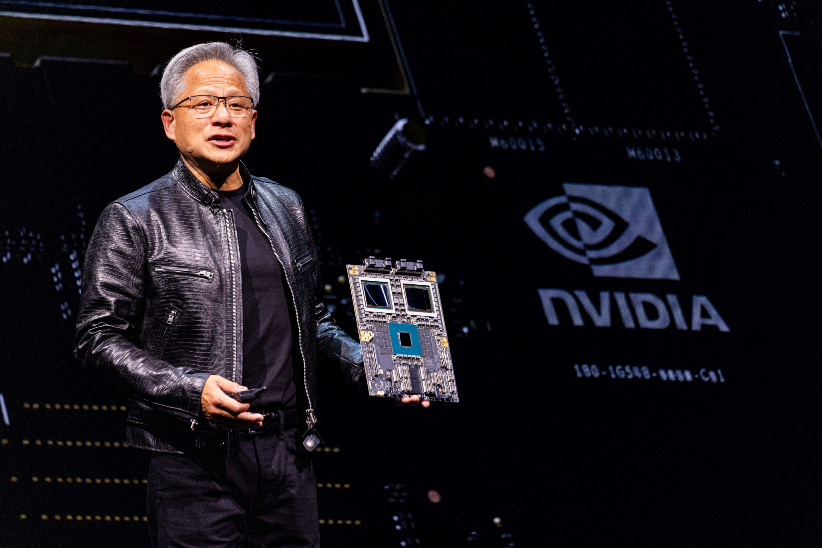 Nvidia CEO Jensen Huang on stage holding one of the company's forthcoming Blackwell Ultra AI chips.