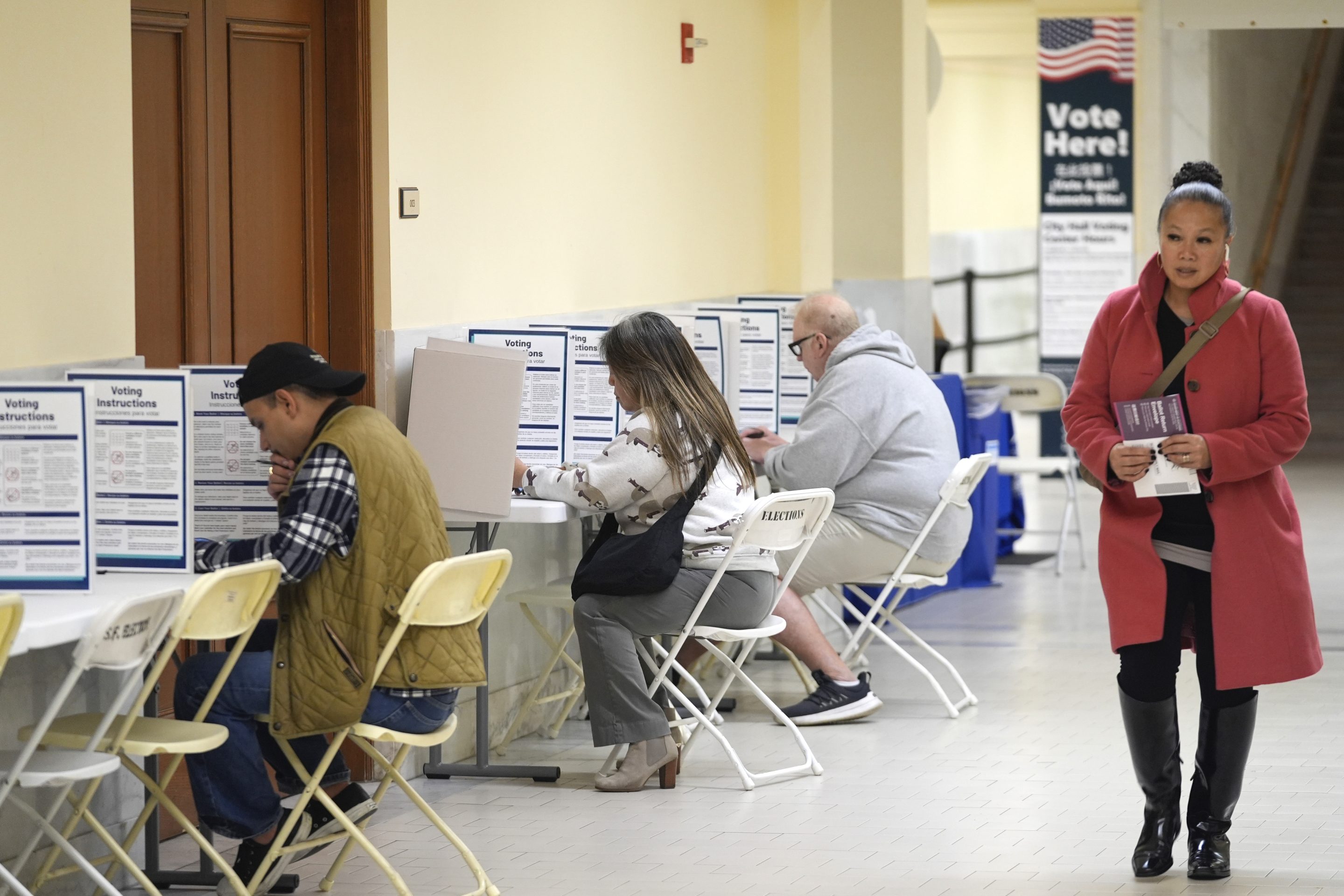 A woman walks with her ballot to a vacant voting booth at City Hall in San Francisco, March 5, 2024.