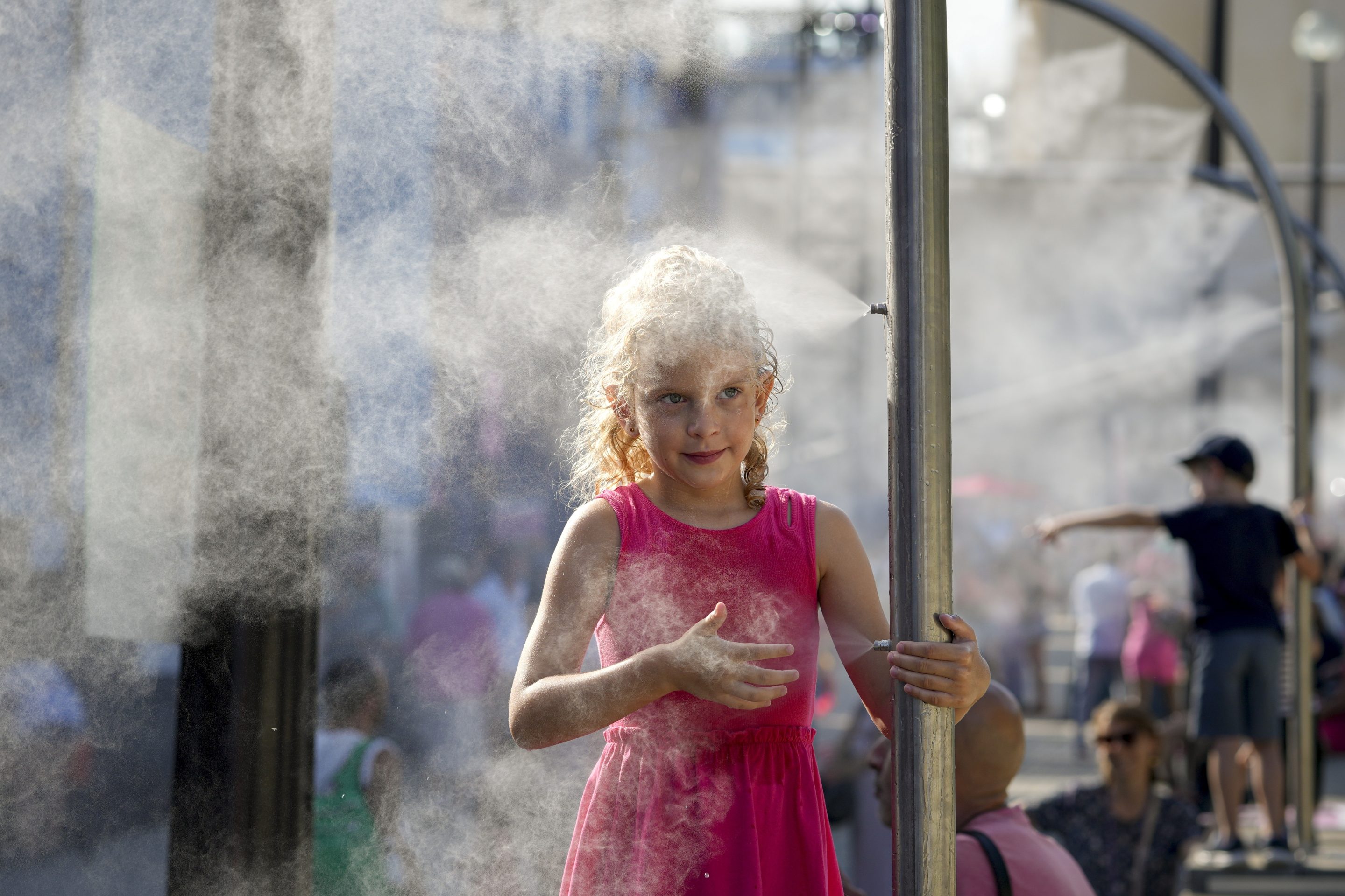 Anna, 7, cools off under a misting fountain on a hot afternoon during the 2024 Summer Olympics, on July 29, 2024, in Paris.