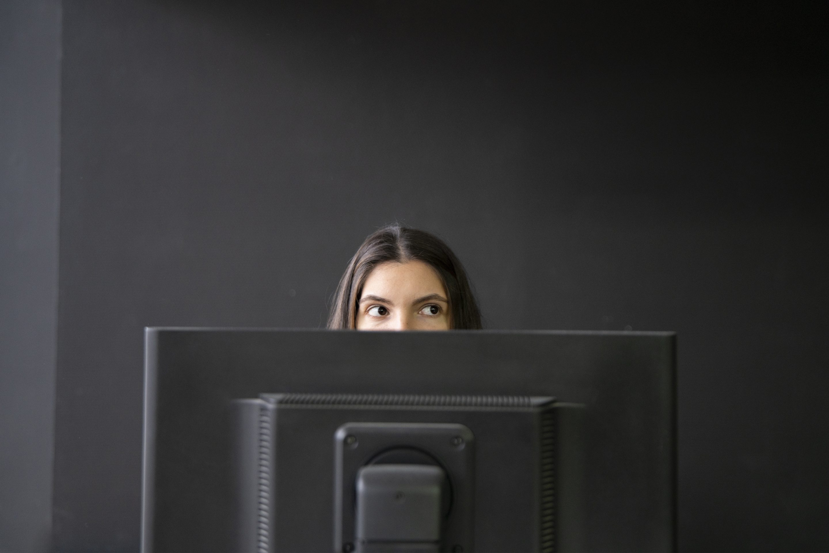 Office worker being sneaky behind computer.