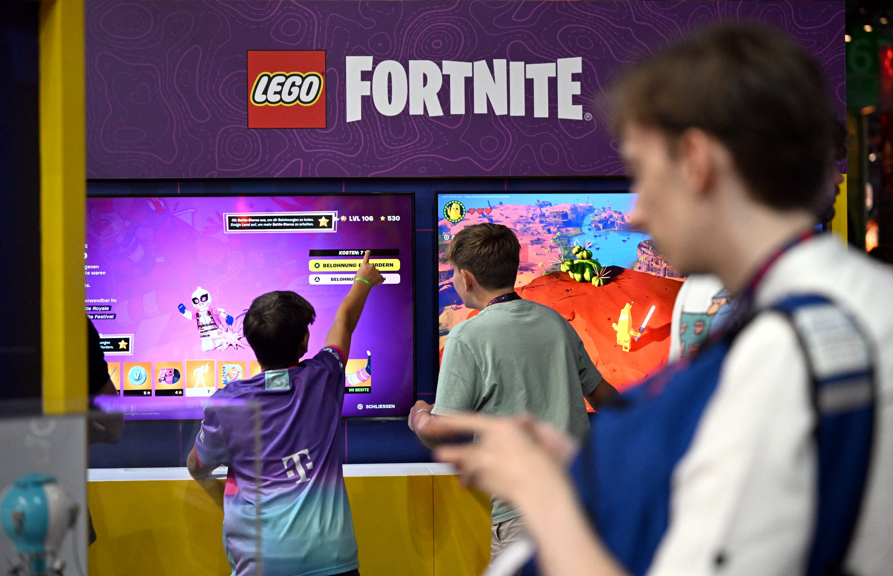 Visitors stand at the booth of 'Lego Fortnite', an open world survival video game, developed and published by Epic Games in association with The Lego Group, during the media day at the Gamescom video games trade fair in Cologne, western Germany on August 21, 2024.