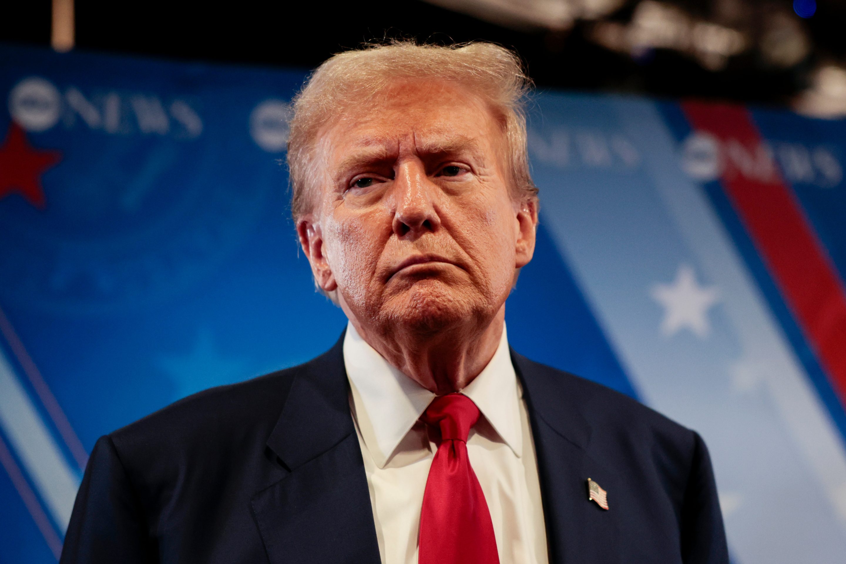 Trump appears with a straight face after the debate Tuesday night. He is wearing a dark blazer and a bright red tie.
