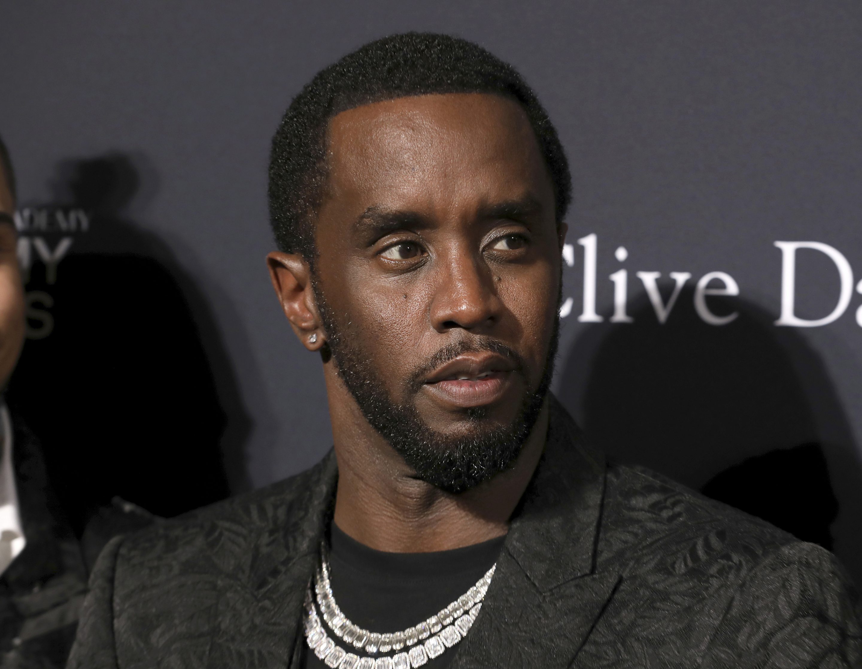 Sean Combs at a red carpet event wearing all black and some ice.