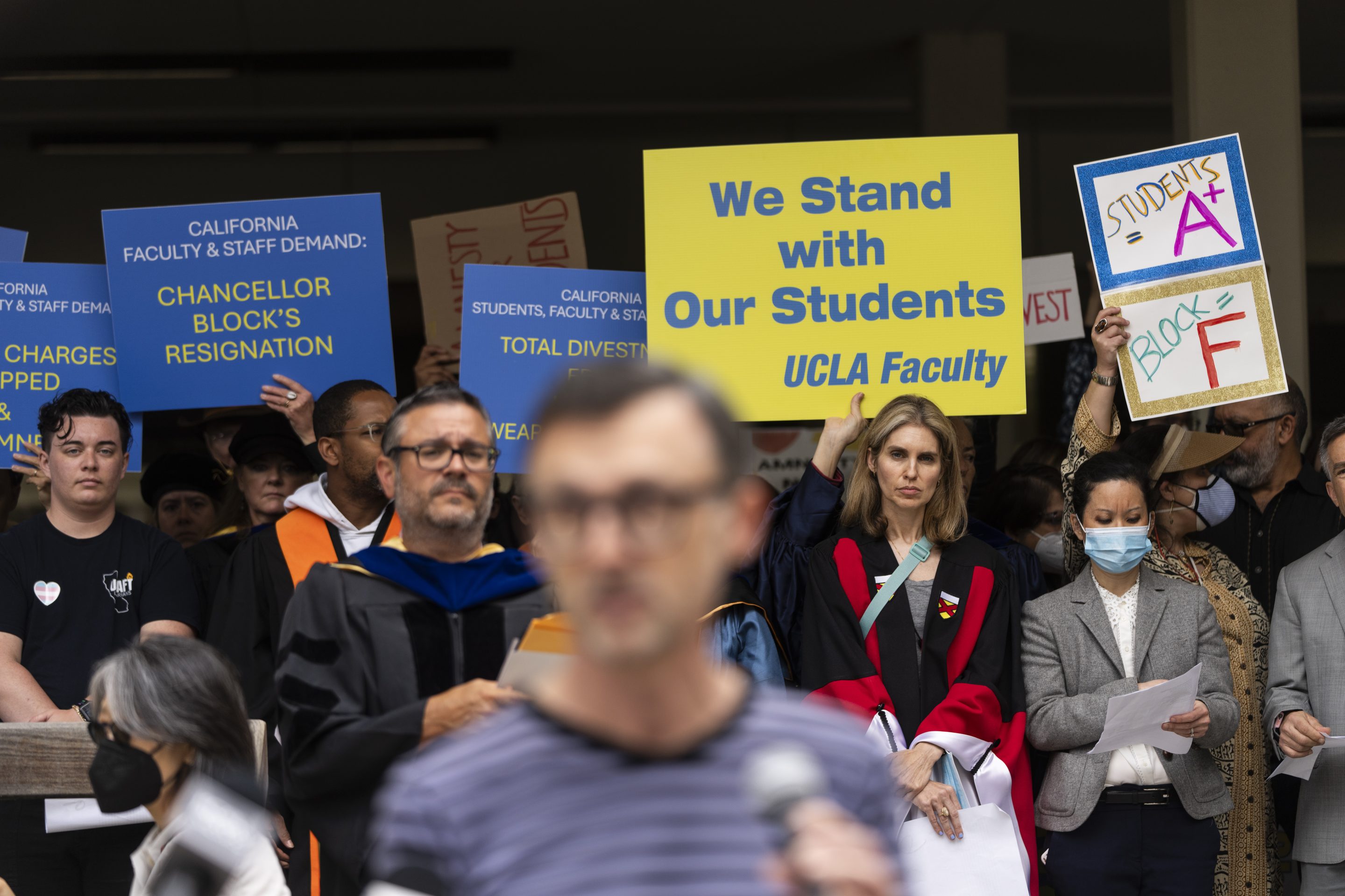 UCLA faculty and staff members hold up signs during a news conference at UCLA in Los Angeles, on May 9, 2024.