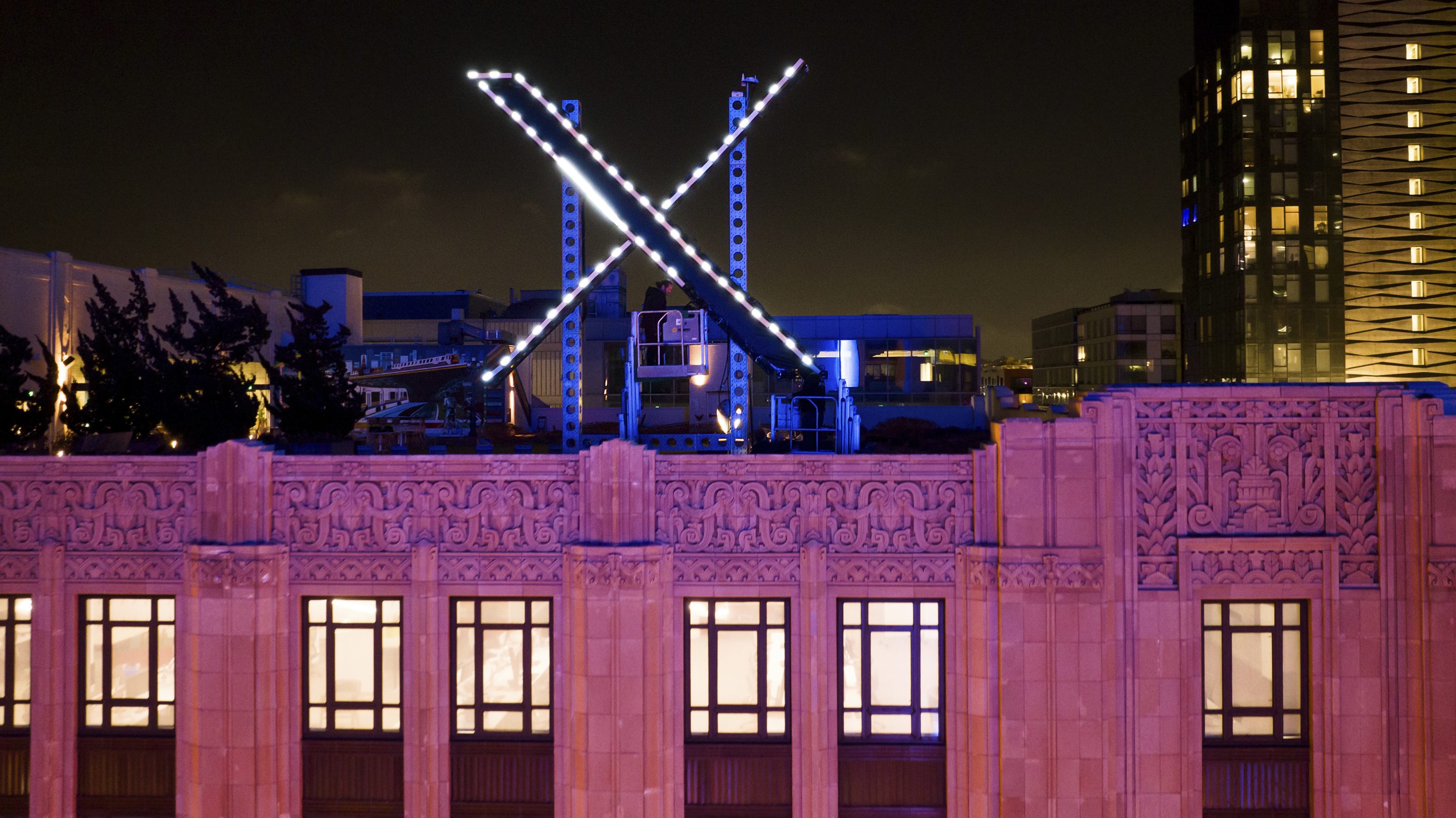 Workers install lighting on an "X" sign atop the company headquarters, formerly known as Twitter, in downtown San Francisco, July 28, 2023.