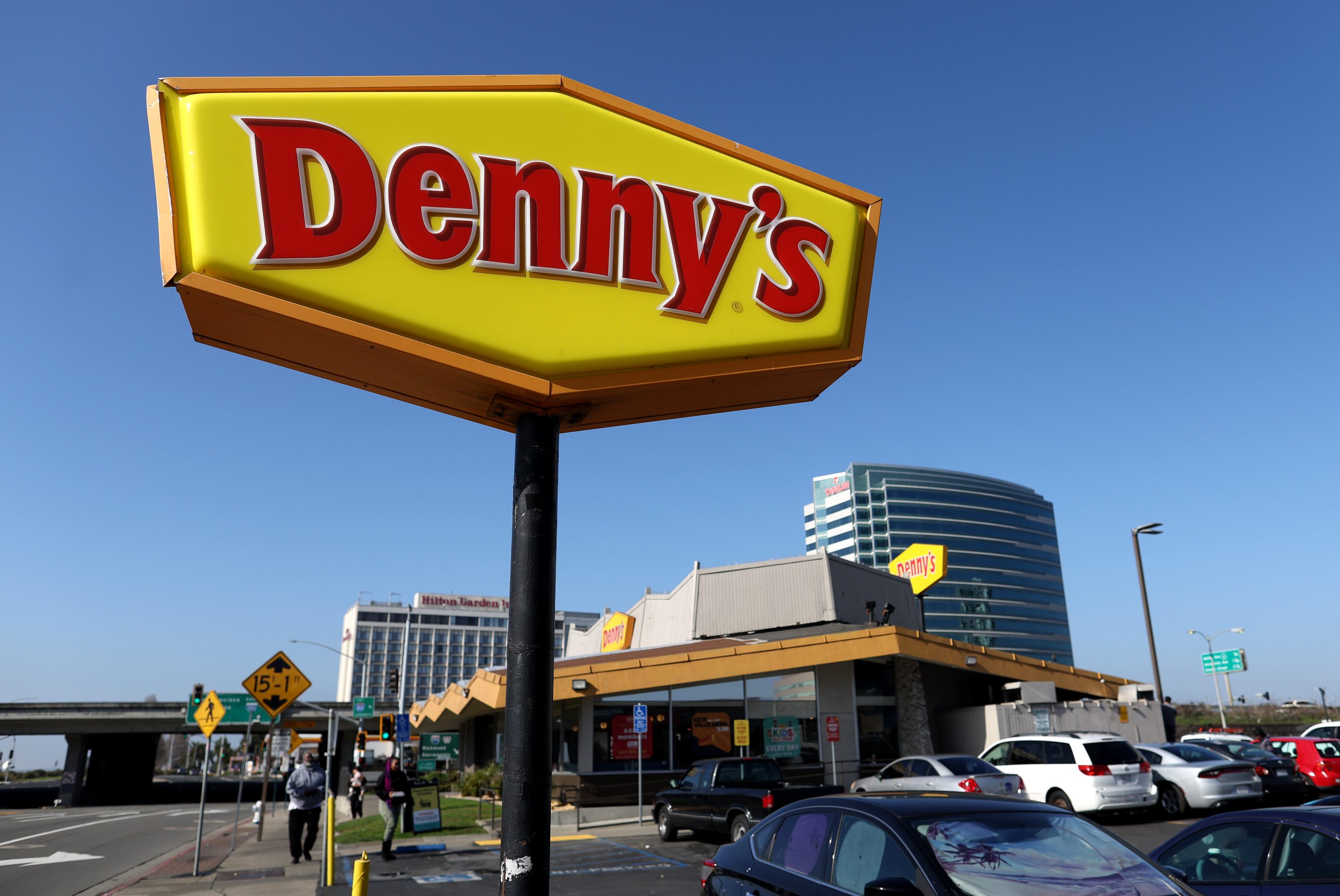A sign is posted in front of a Denny's restaurant