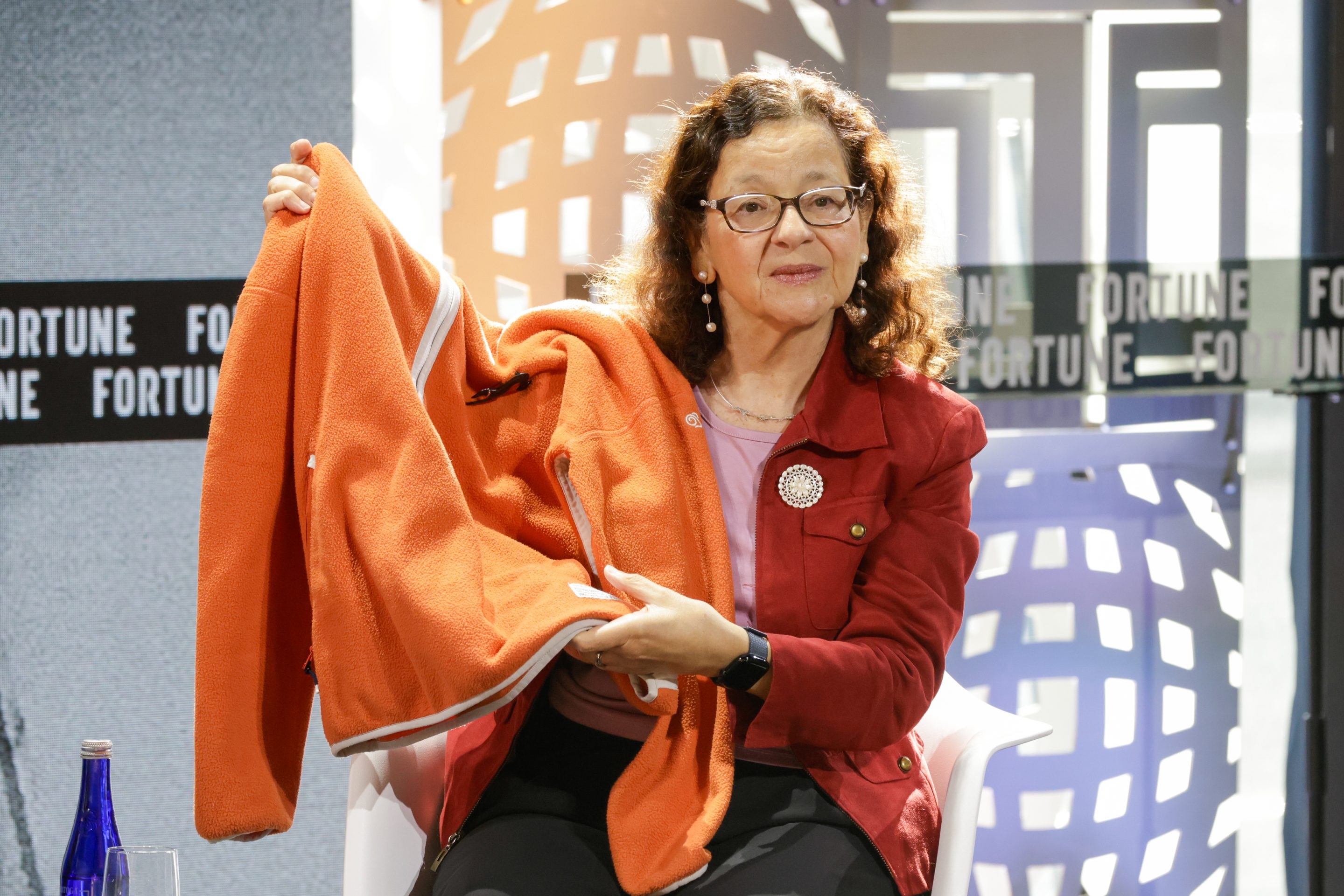 Dr. Jennifer Holmgren holds up an orange jacket, which was converted from pollution using biorecycling