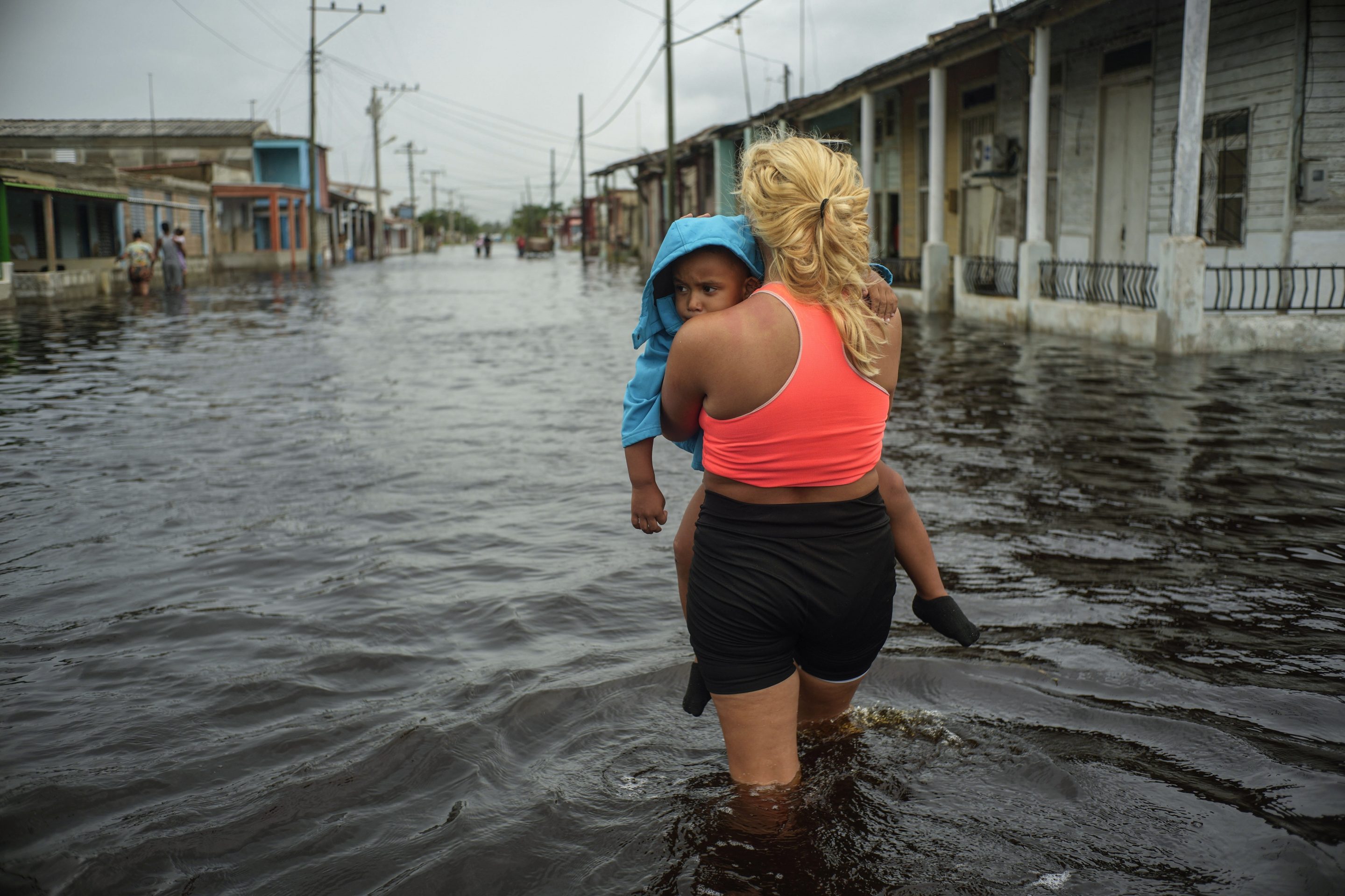 A woman carries a child as she wades through a street flooded in the passing of Hurricane Helene, in Batabano, Mayabeque province, Cuba, Sept. 26, 2024.