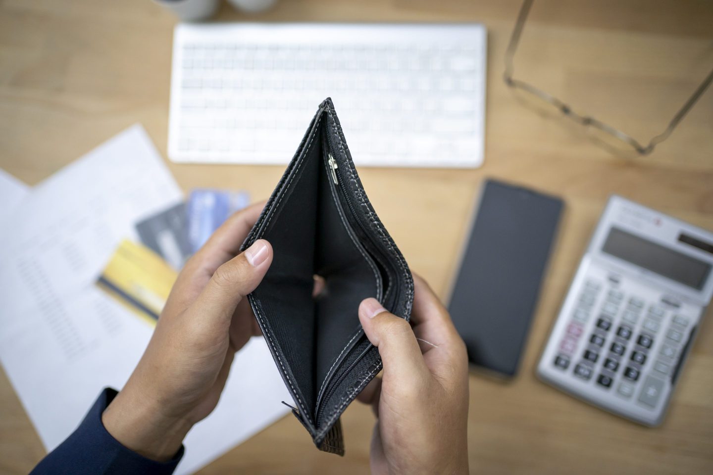Empty wallet, calculator and budgeting tools in the background.