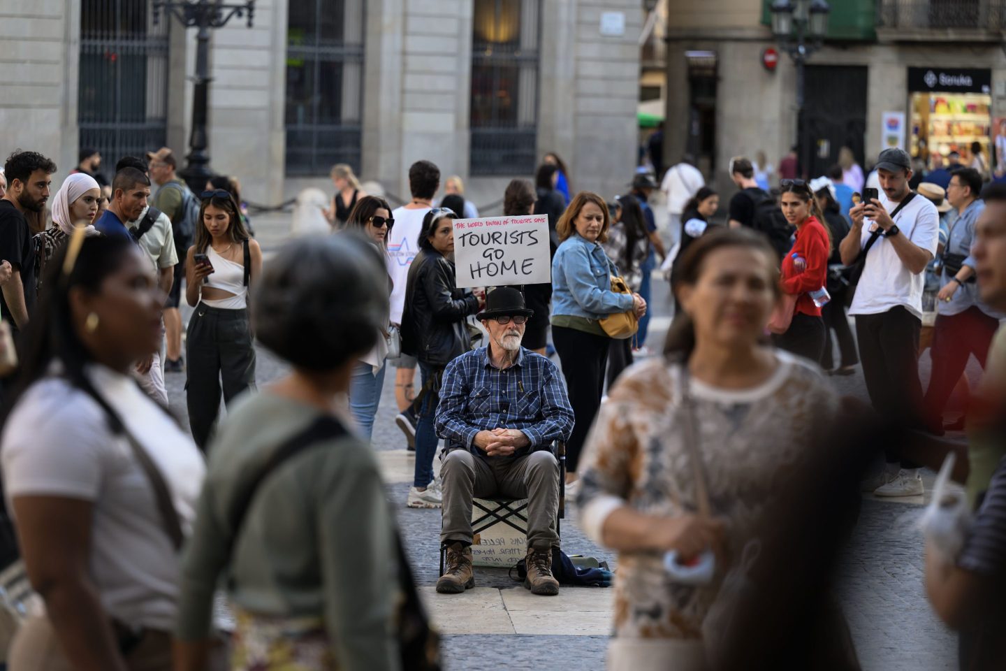 An activist holds a sign saying “Tourists Go Home” in Barcelona in November 2024.