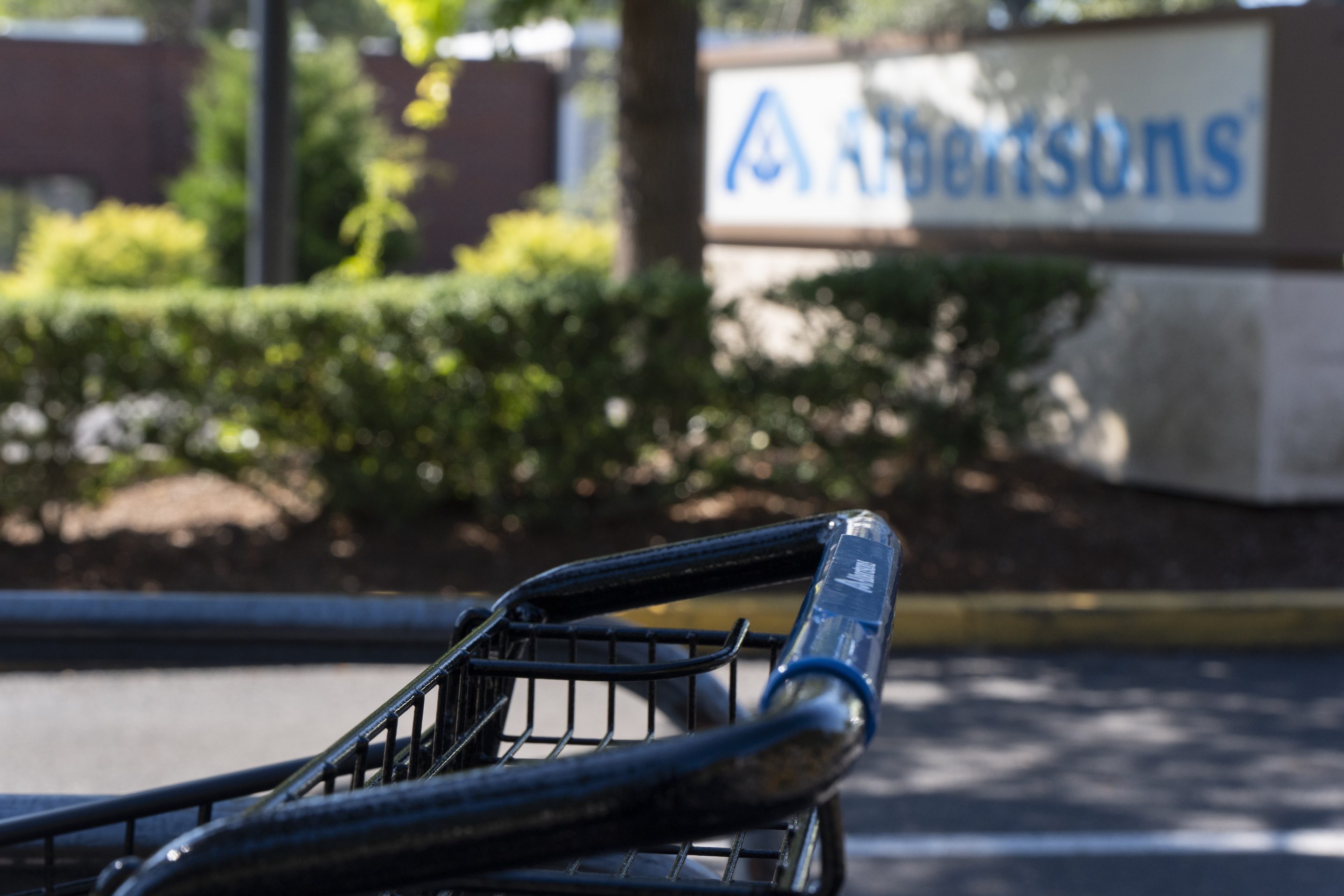 A grocery cart rests in a cart return area with a sign for Albertsons grocery store in the background on Aug. 26, 2024, in Lake Oswego, Ore.