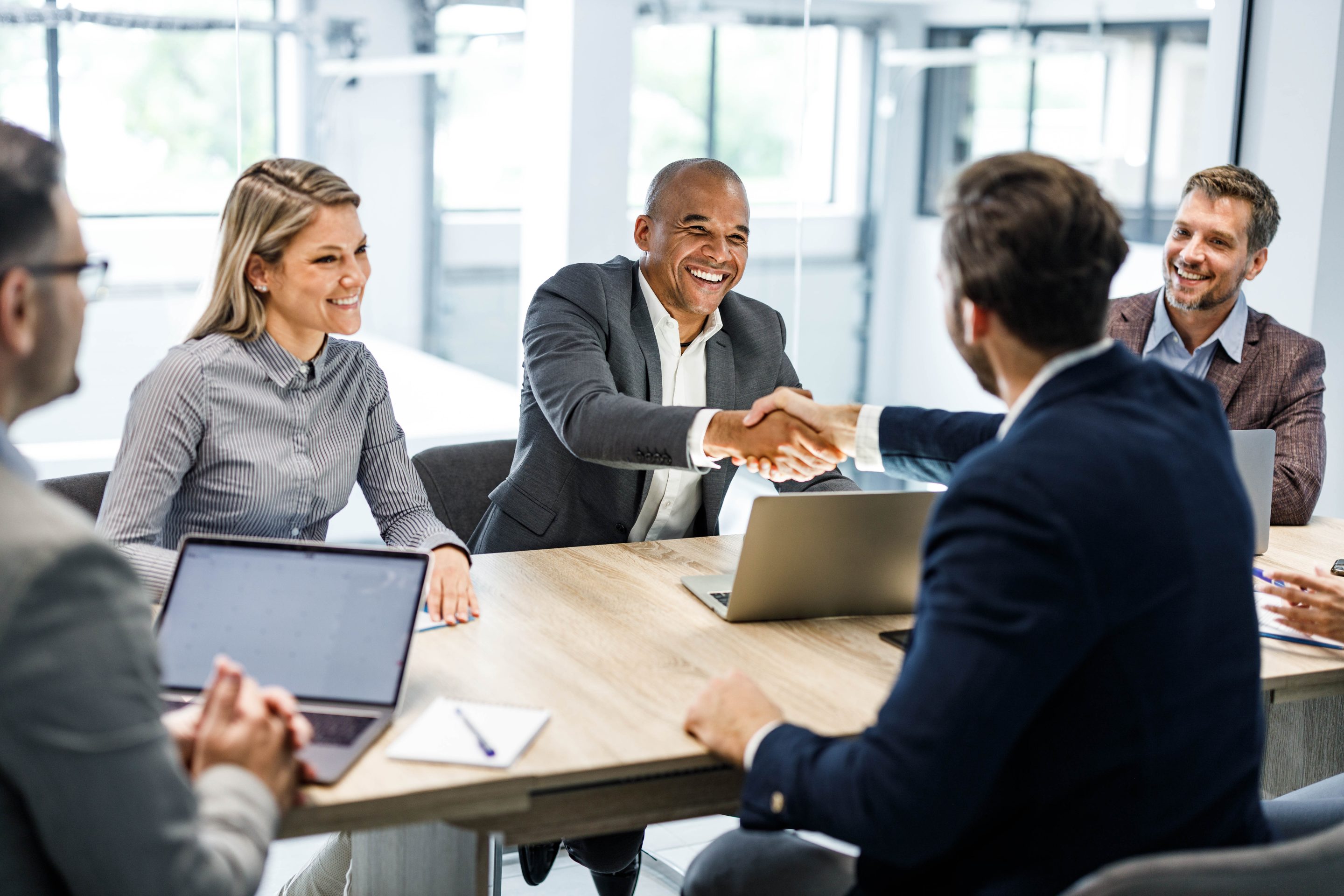 business professionals smiling and shaking hands in a meeting room