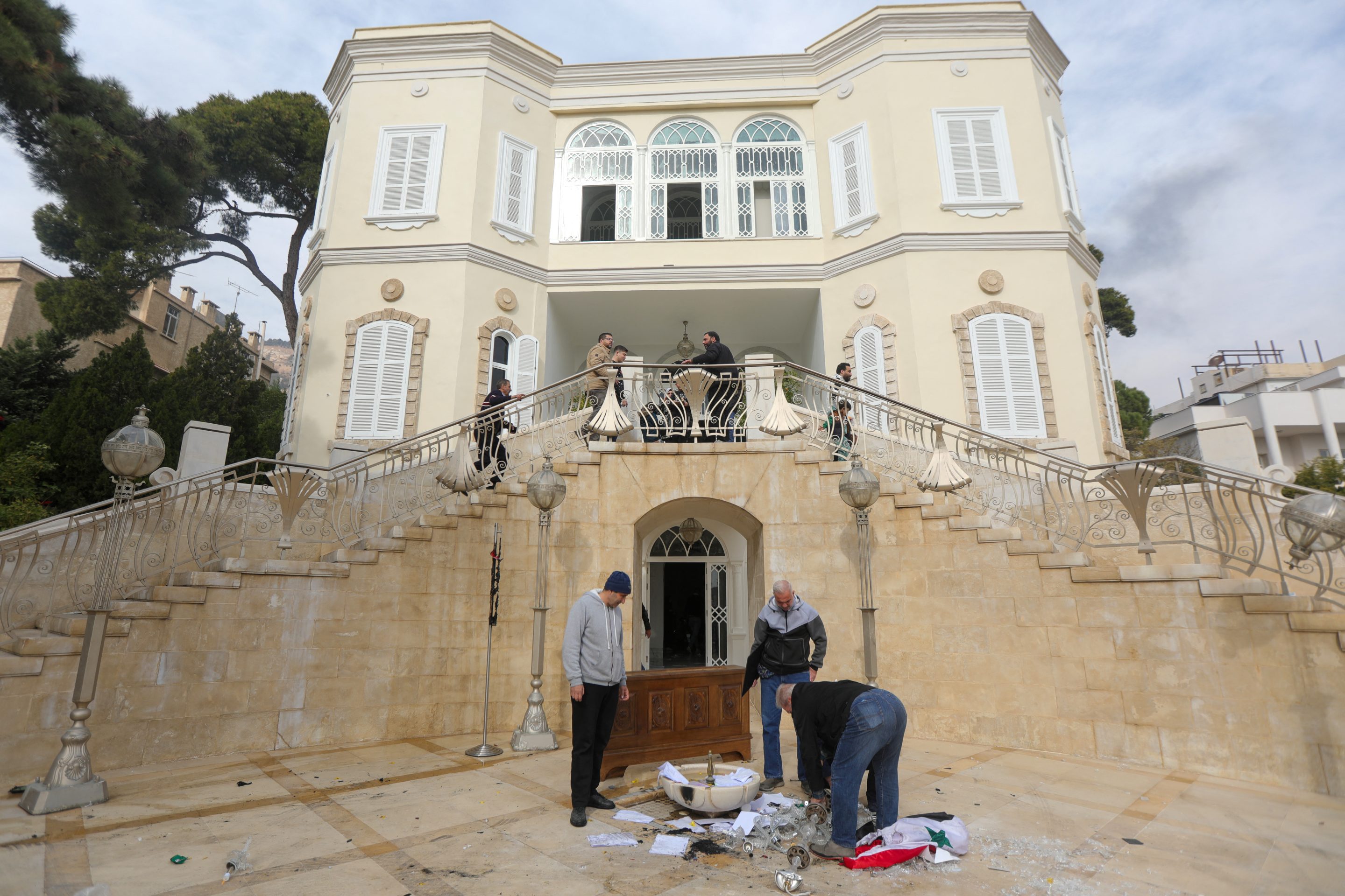 People remove the Syrian flag from the entrance of ousted president Bashar al-Assad's residence in Damascus on Sunday.