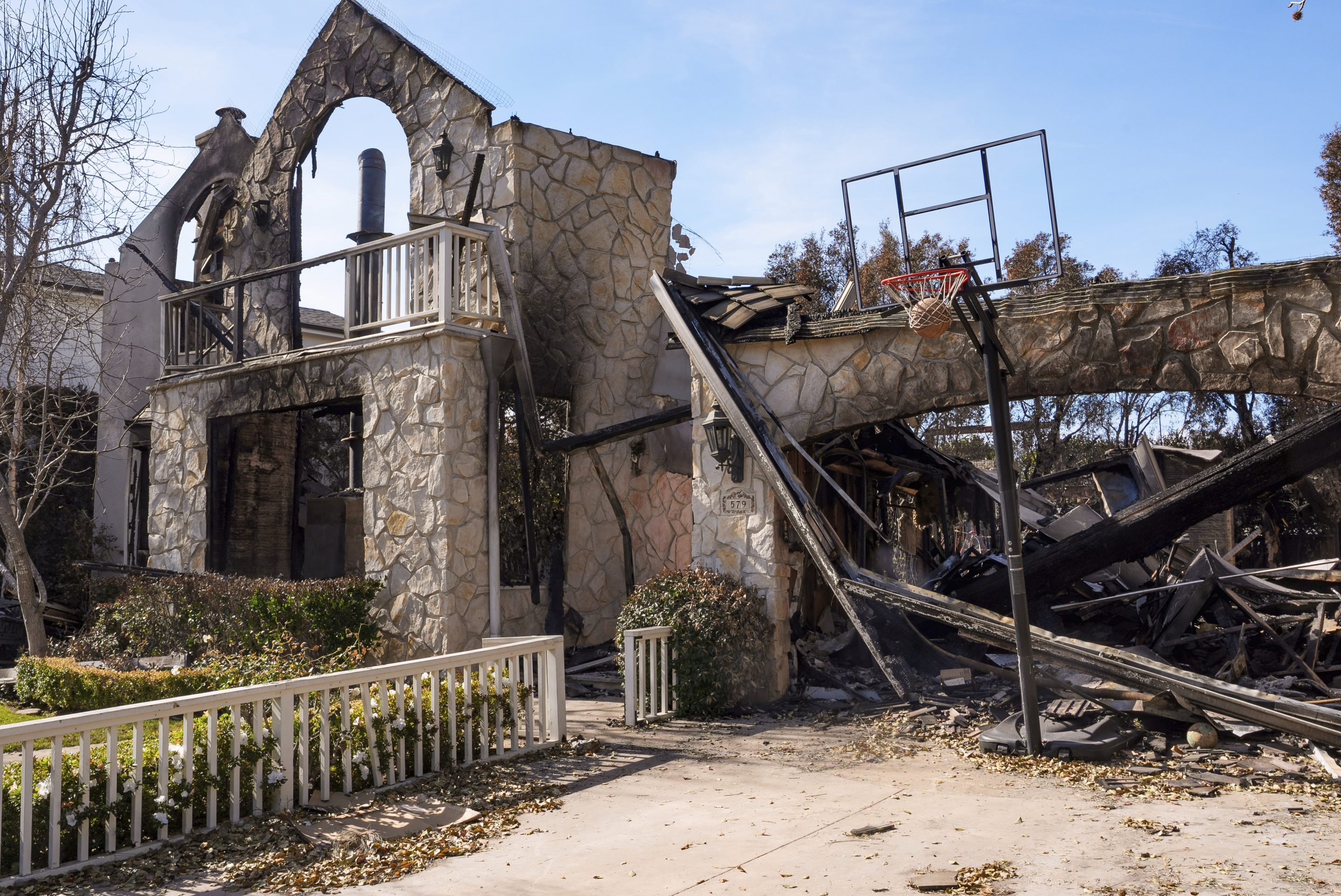 A basketball is stuck in the net outside of a residence destroyed by the Palisades Fire in the Pacific Palisades neighborhood of Los Angeles, on Jan. 24, 2025.