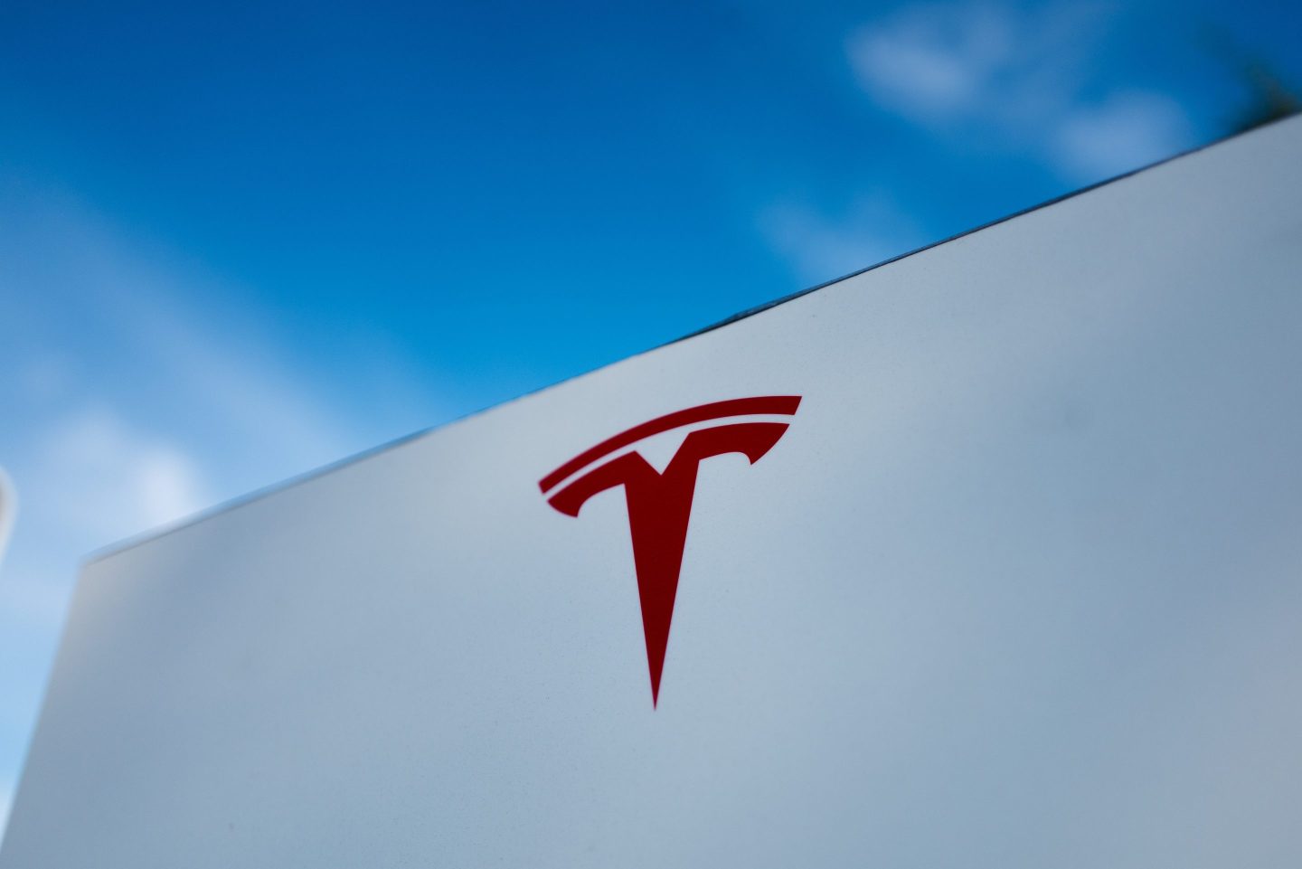 Close-up of Tesla Motors logo against a bright blue sky