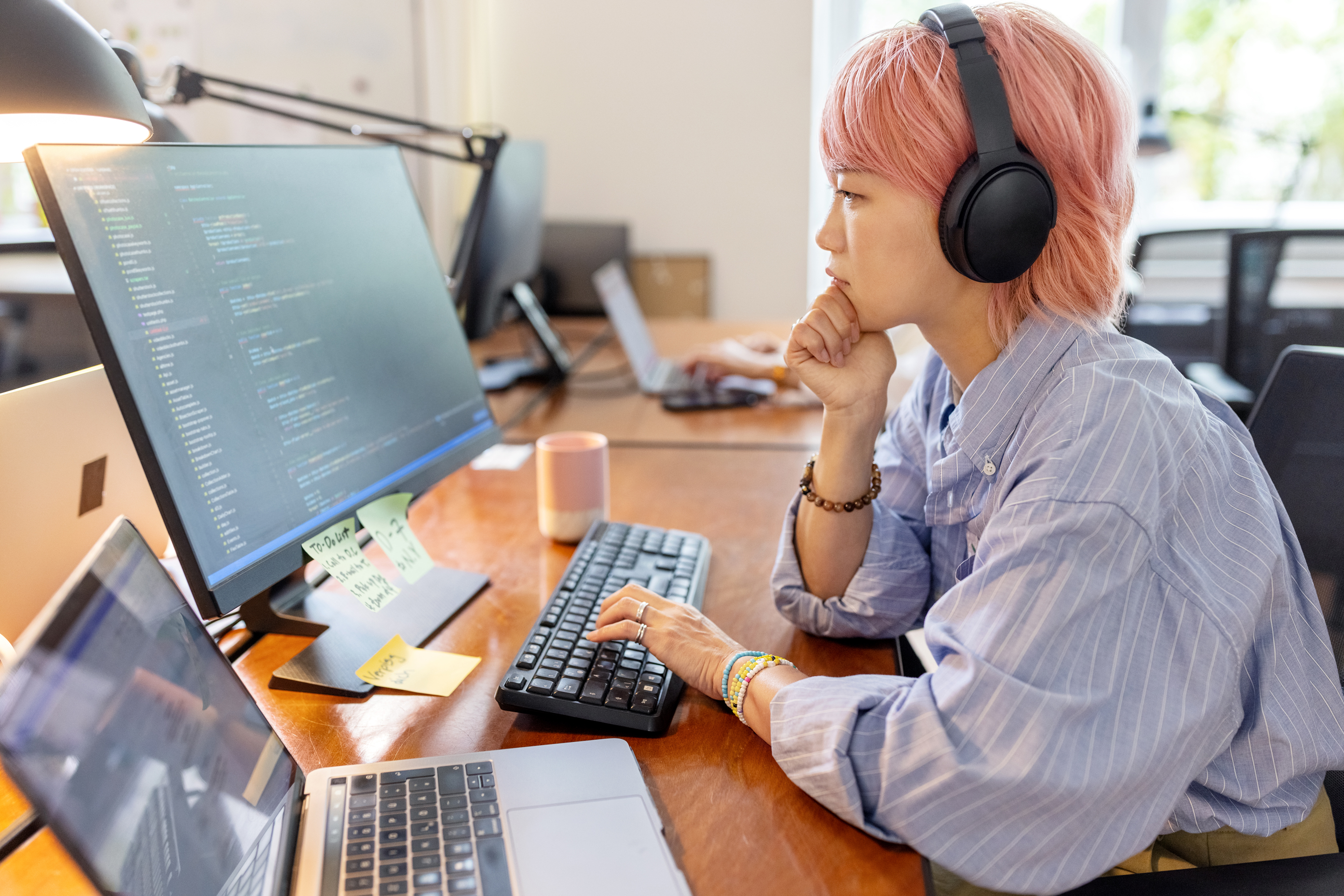 Side view of a woman computer programmer working at her desk at a startup company.